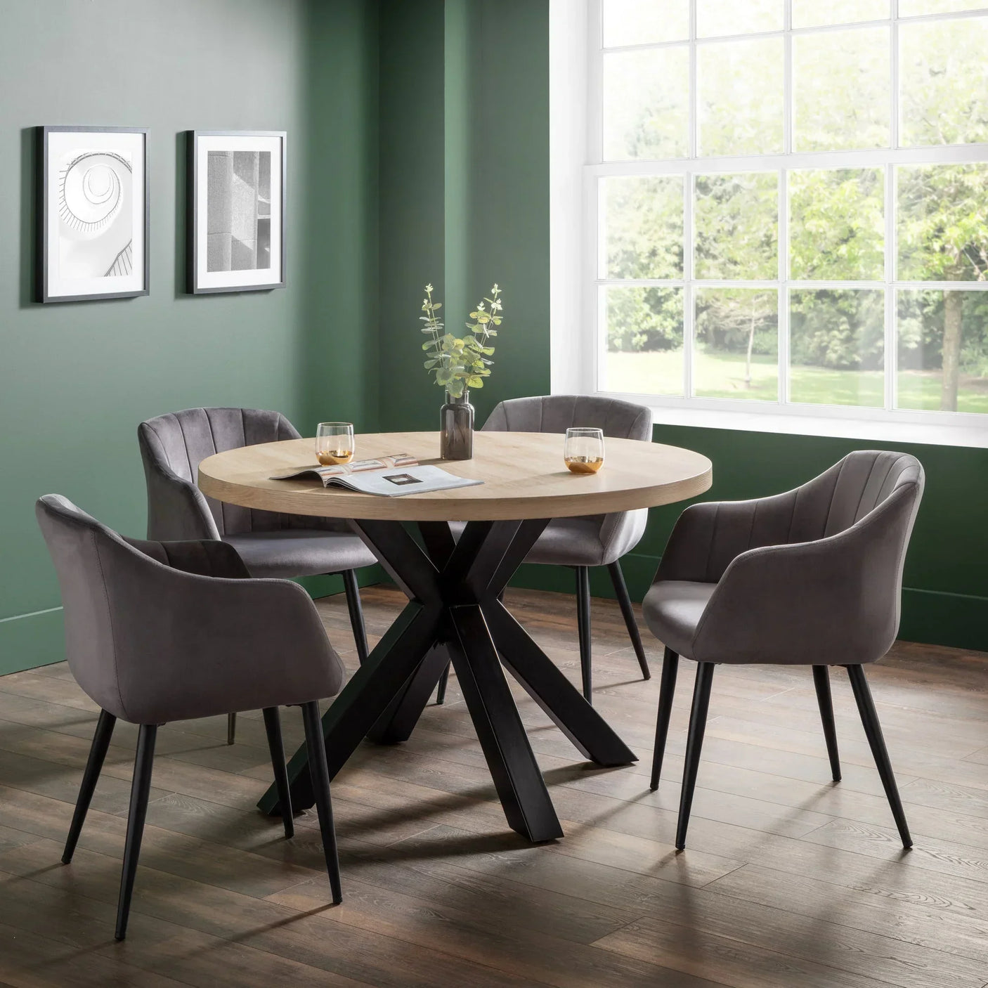 Round dining table with light wood top and four grey velvet chairs in modern dining room