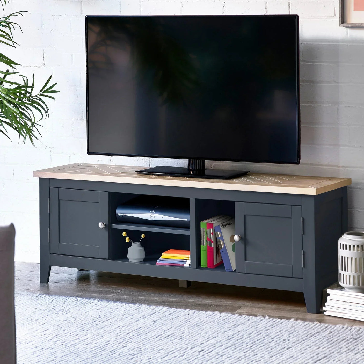 Dark grey wooden TV unit with oak top, storage shelves, and side cabinets in living room