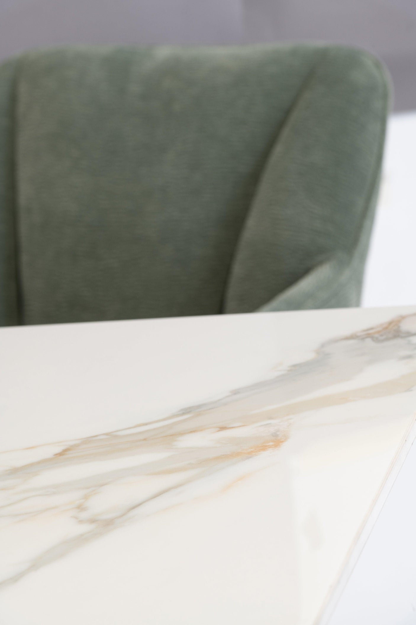 Close up of marble dining table corner with green upholstered dining chair