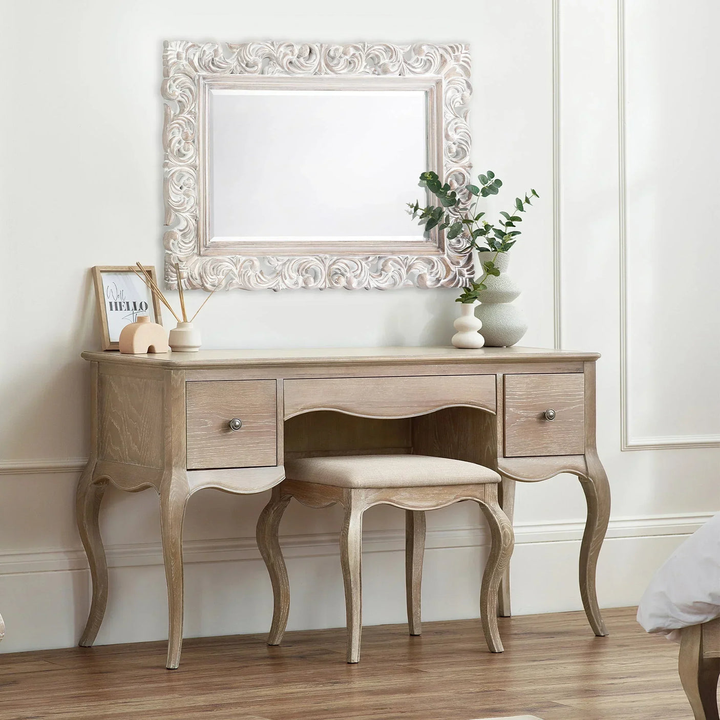 Wooden dressing table with matching stool, ornate mirror, and decor in a bright bedroom
