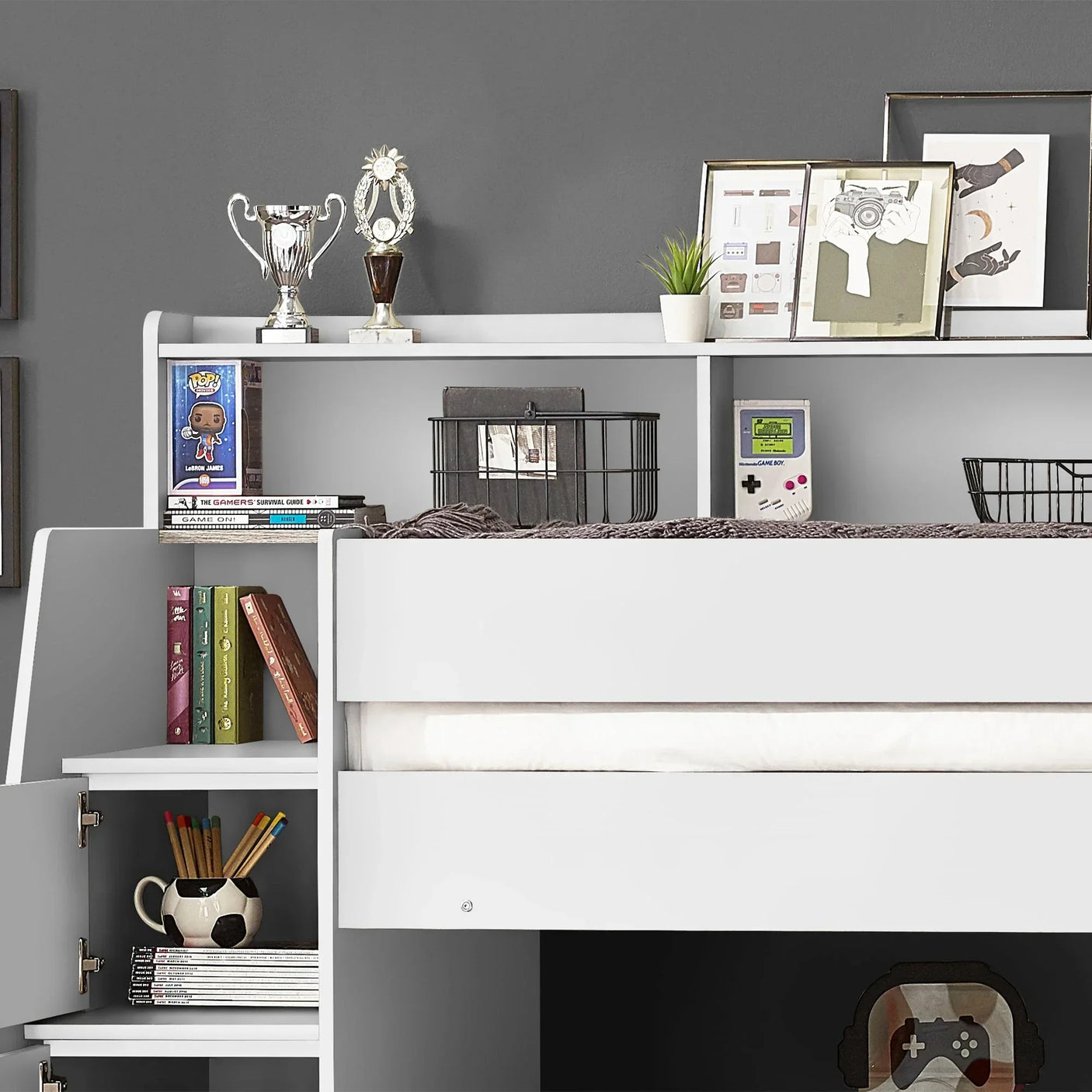 White staircase bunk bed with storage shelves, books and gaming accessories