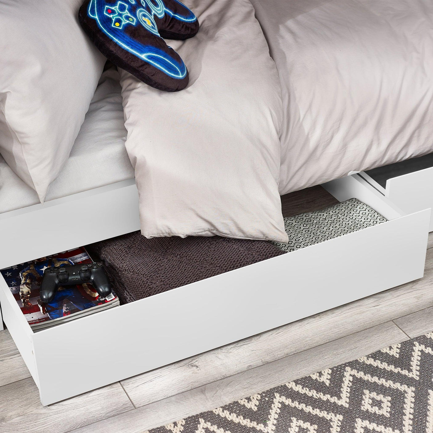 White bunk bed with underbed storage drawer open, showing blankets and games inside