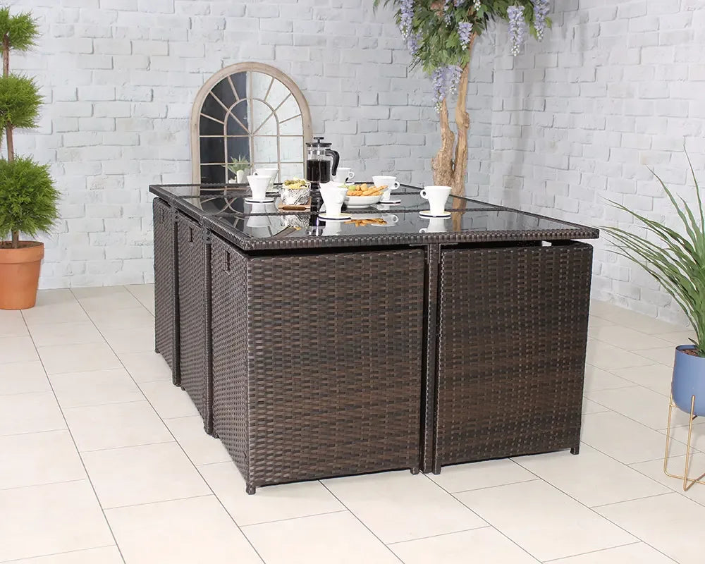 Brown rattan dining set with glass top table arranged for breakfast in modern tiled room