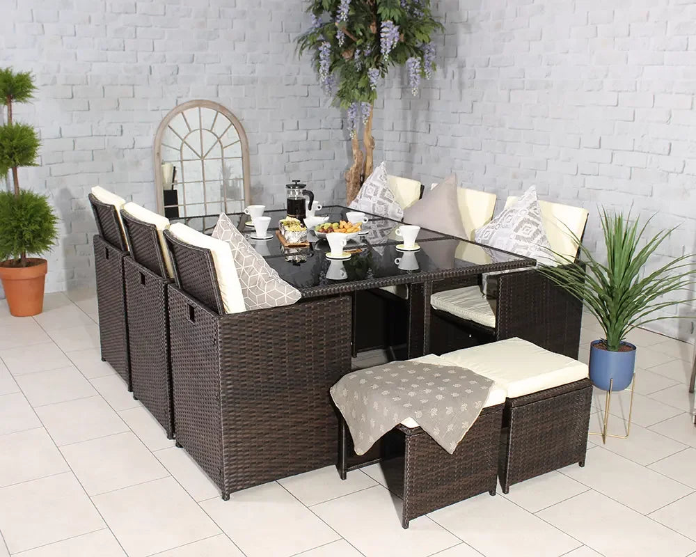 Brown rattan dining set with glass table, cushioned chairs, bench and neutral decor