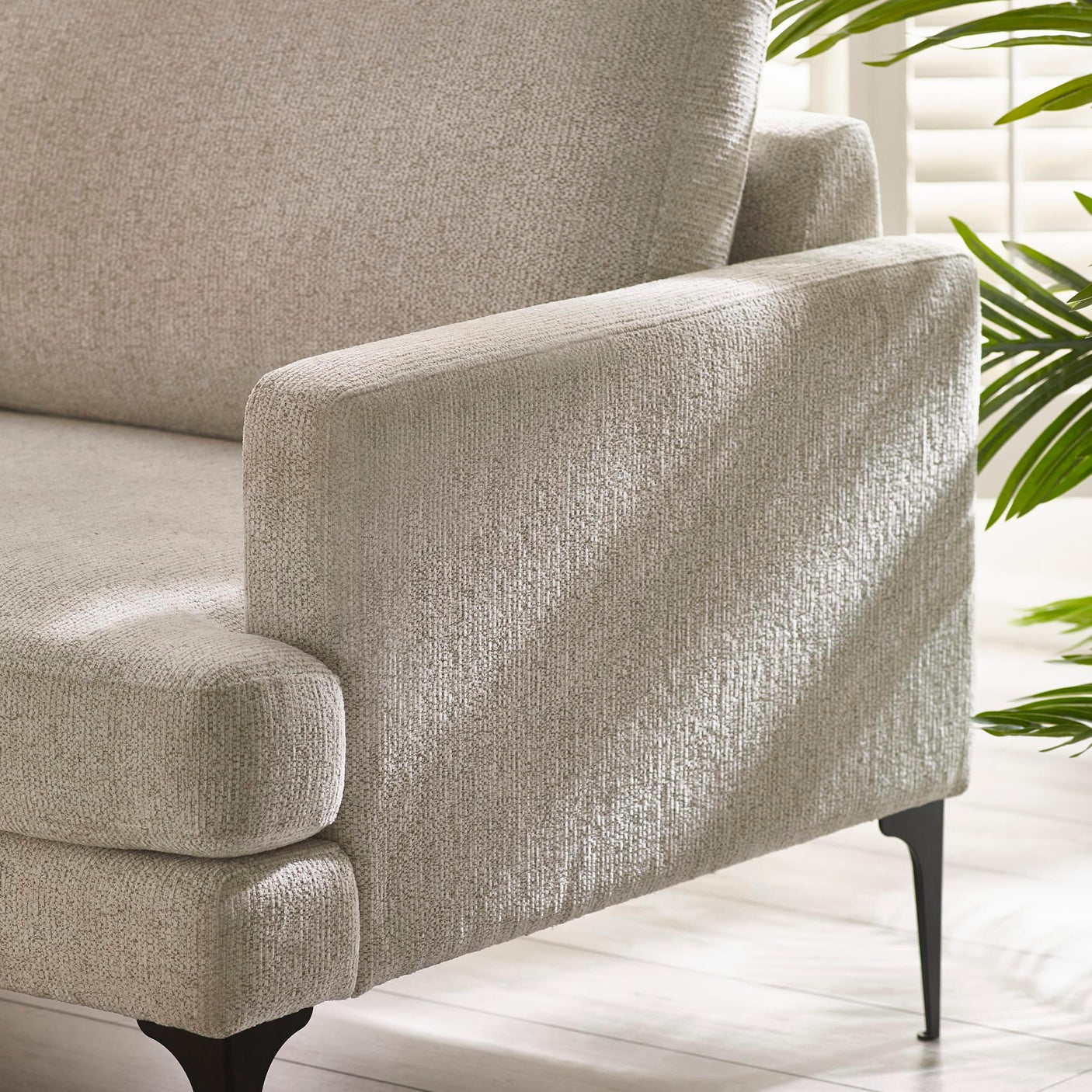 Beige fabric sofa armrest and seat with black metal legs in bright living room