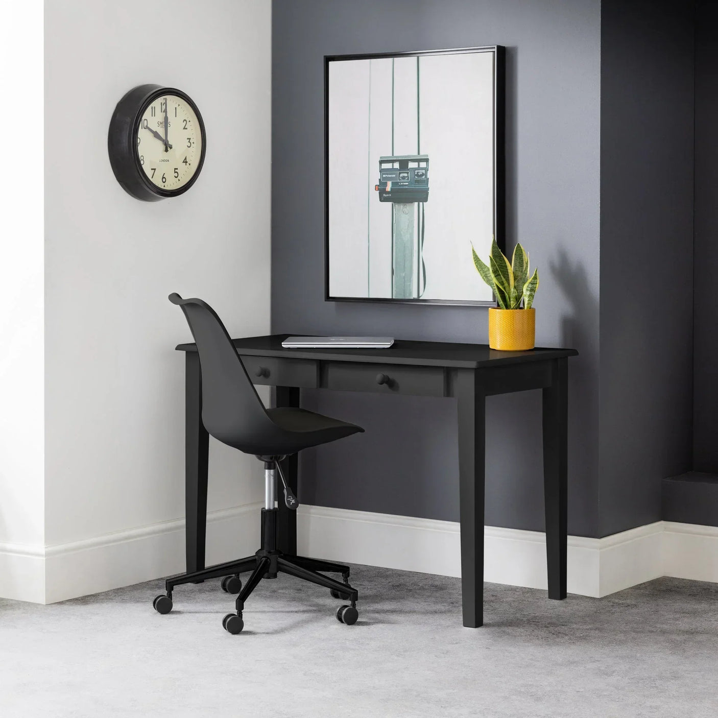 Black desk with drawers in modern room, paired with black office chair and plant