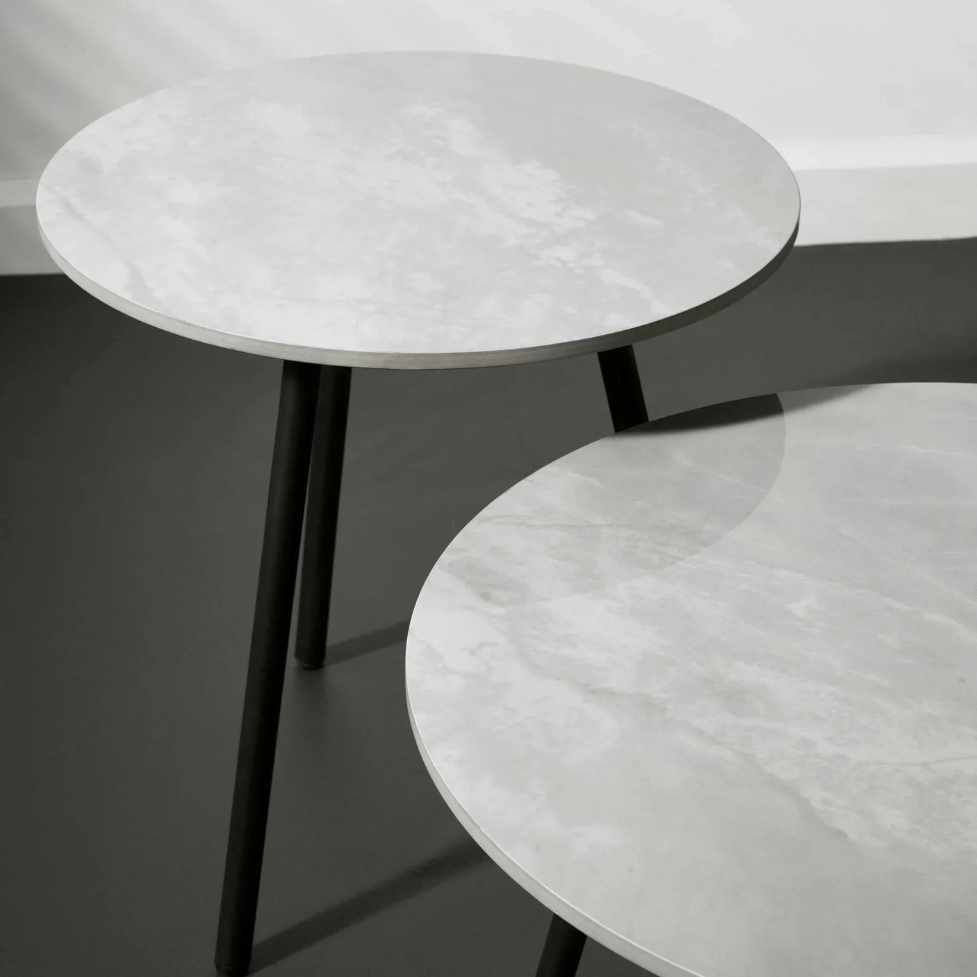 Round marble top side tables with black legs on grey floor