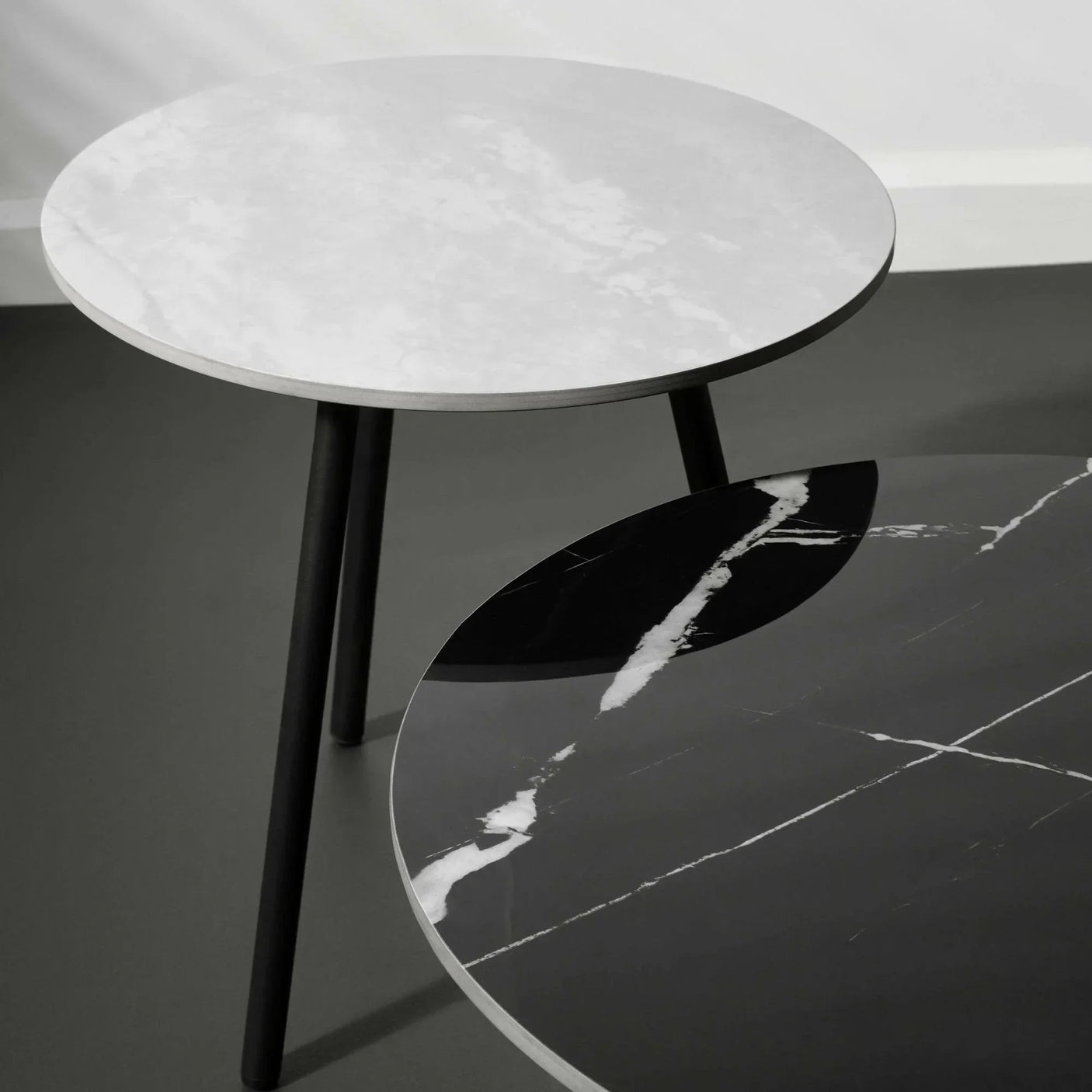 Round marble side tables with black legs, one white marble top and one black marble top
