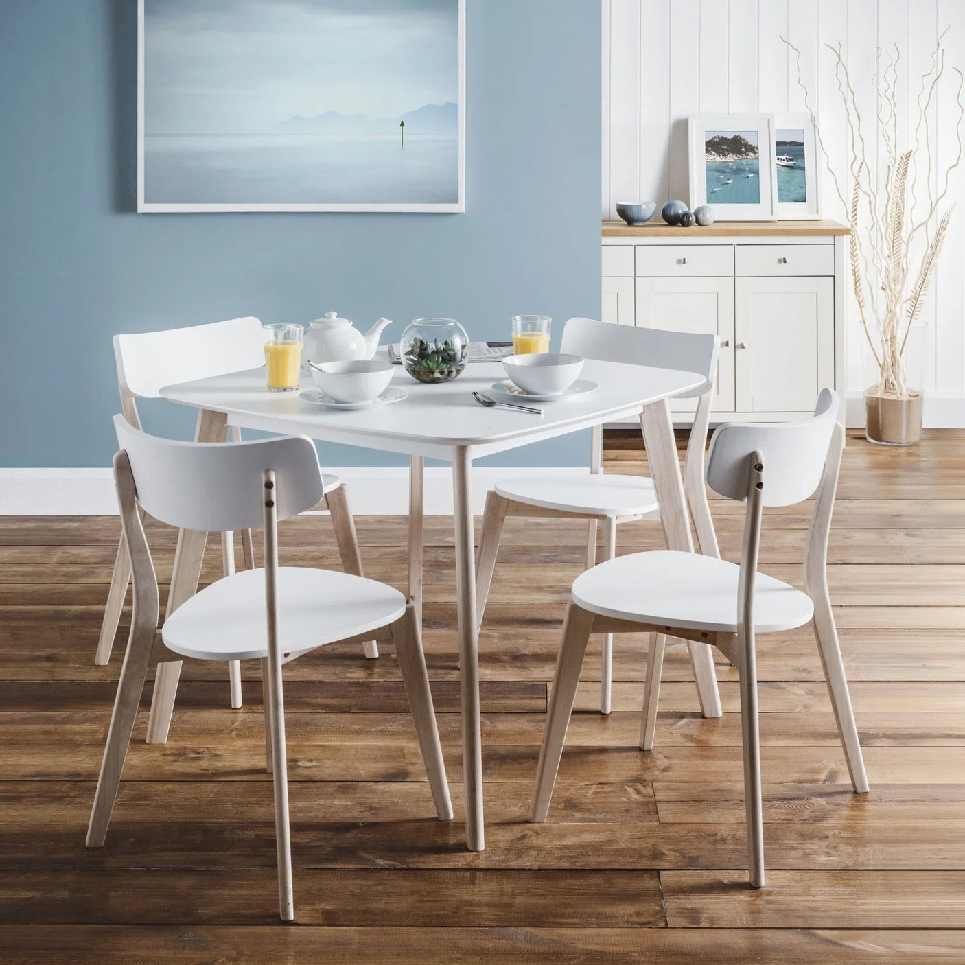 White dining table set with four chairs on wooden floor in modern dining room