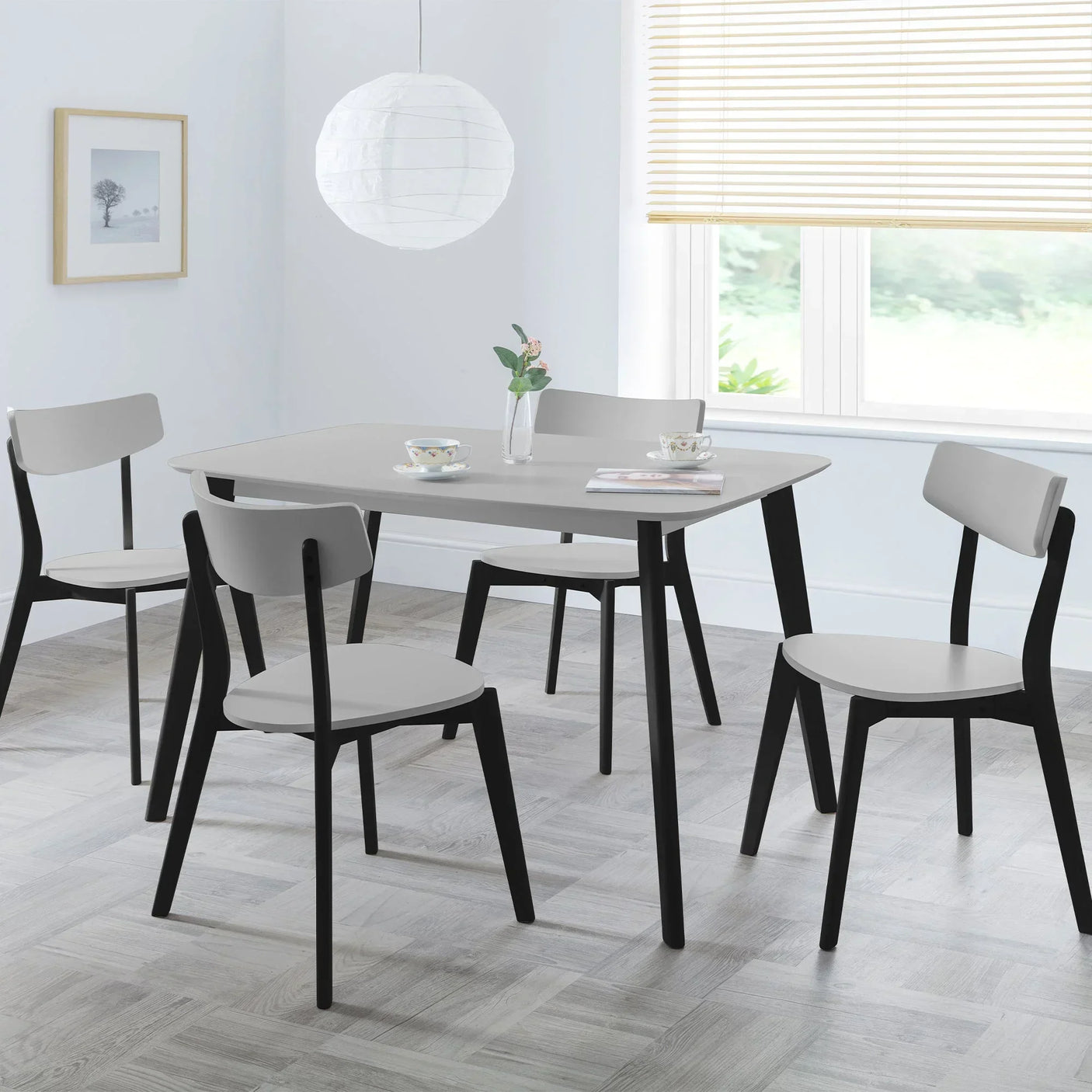 Grey rectangle dining table with black legs and four matching chairs in modern dining room