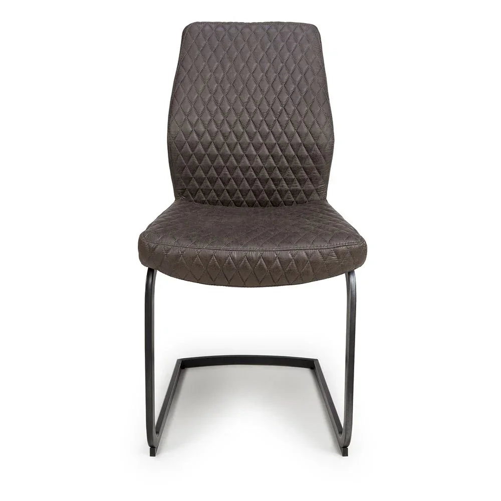 Grey dining chair with diamond stitched upholstery and black cantilever metal legs front view