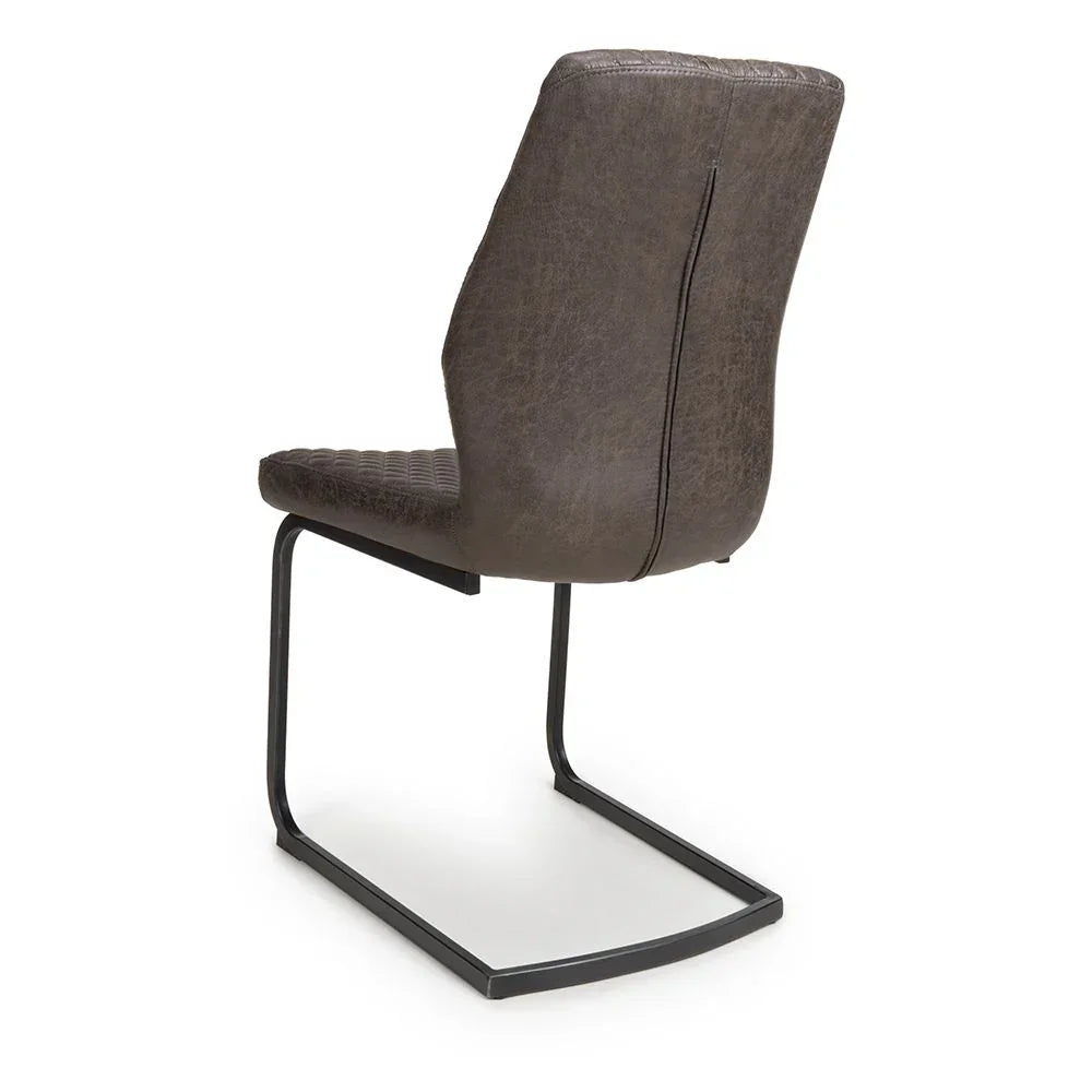 Brown faux leather dining chair with quilted seat and black cantilever metal base, rear view