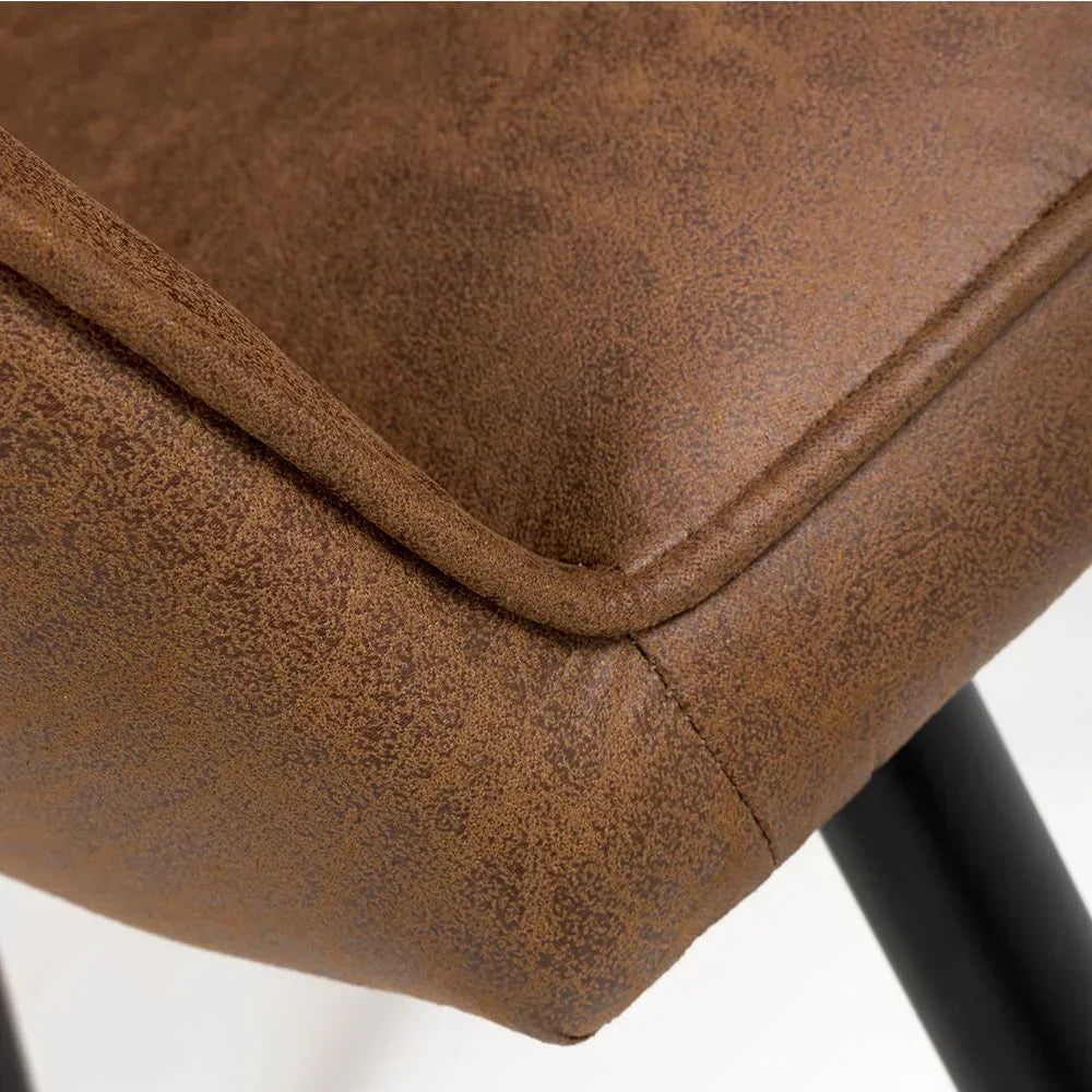 Closeup of brown faux leather dining chair seat with black metal leg