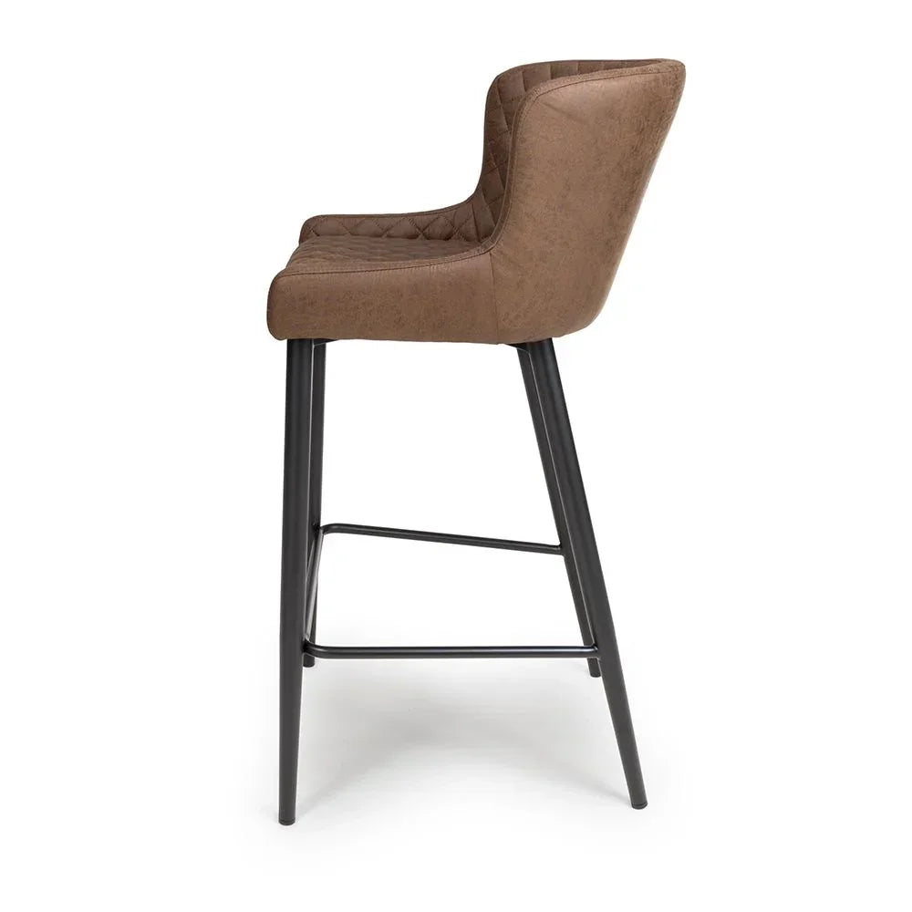 Brown bar stool with padded seat and black metal legs, side view