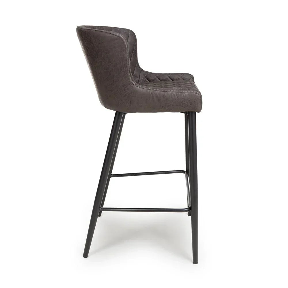Grey bar stool with padded seat and black metal legs side view