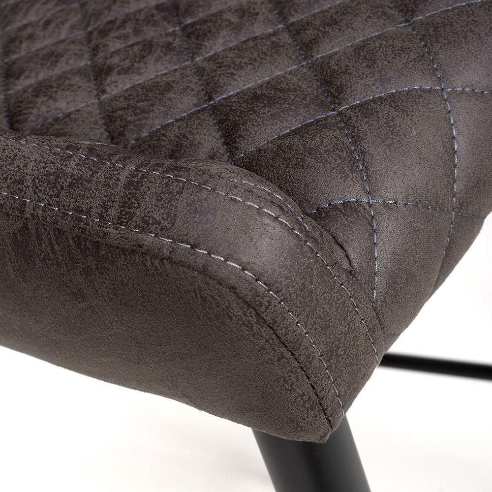 Closeup of grey dining chair seat with diamond stitching and black metal legs