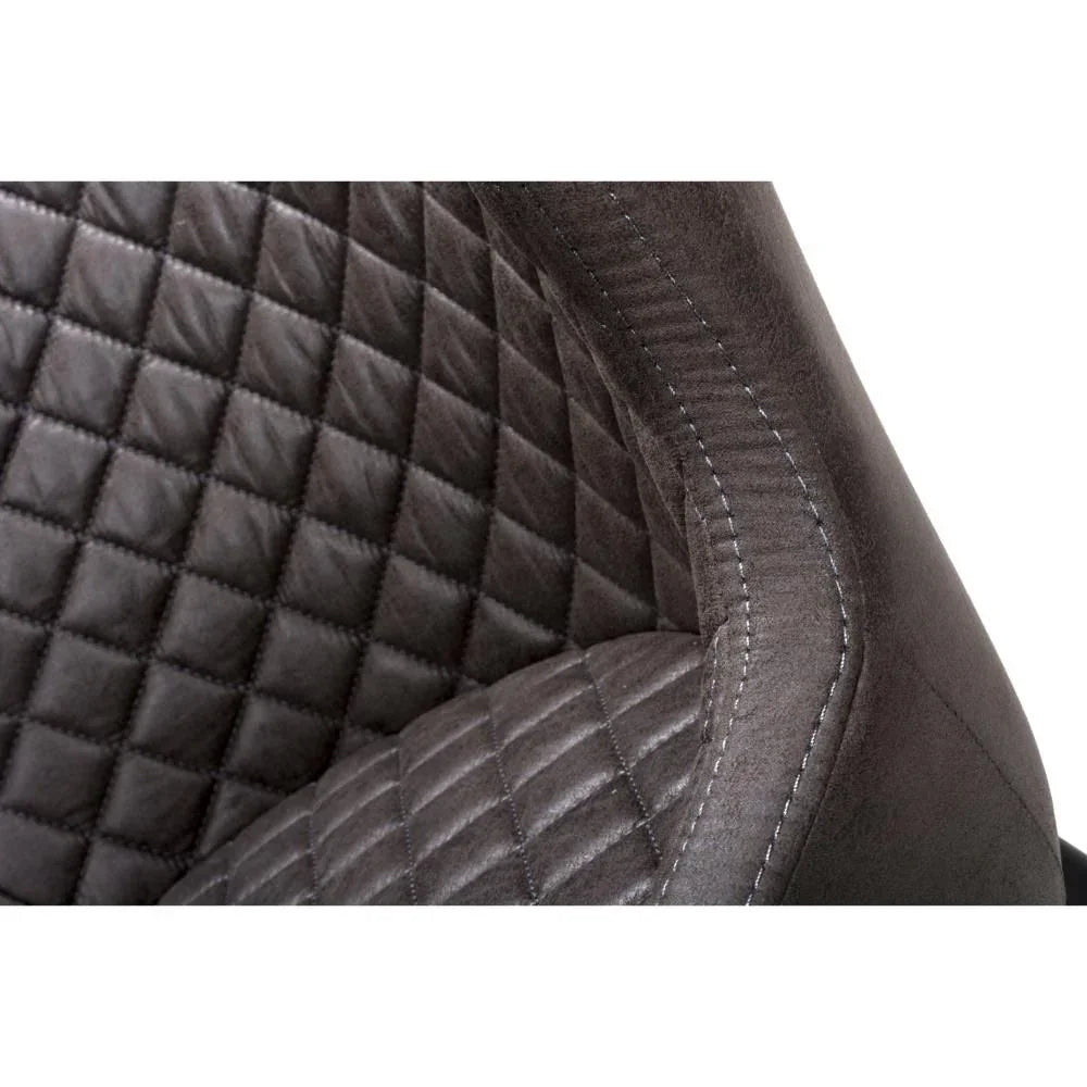 Closeup of grey dining chair with quilted upholstery and detailed stitching