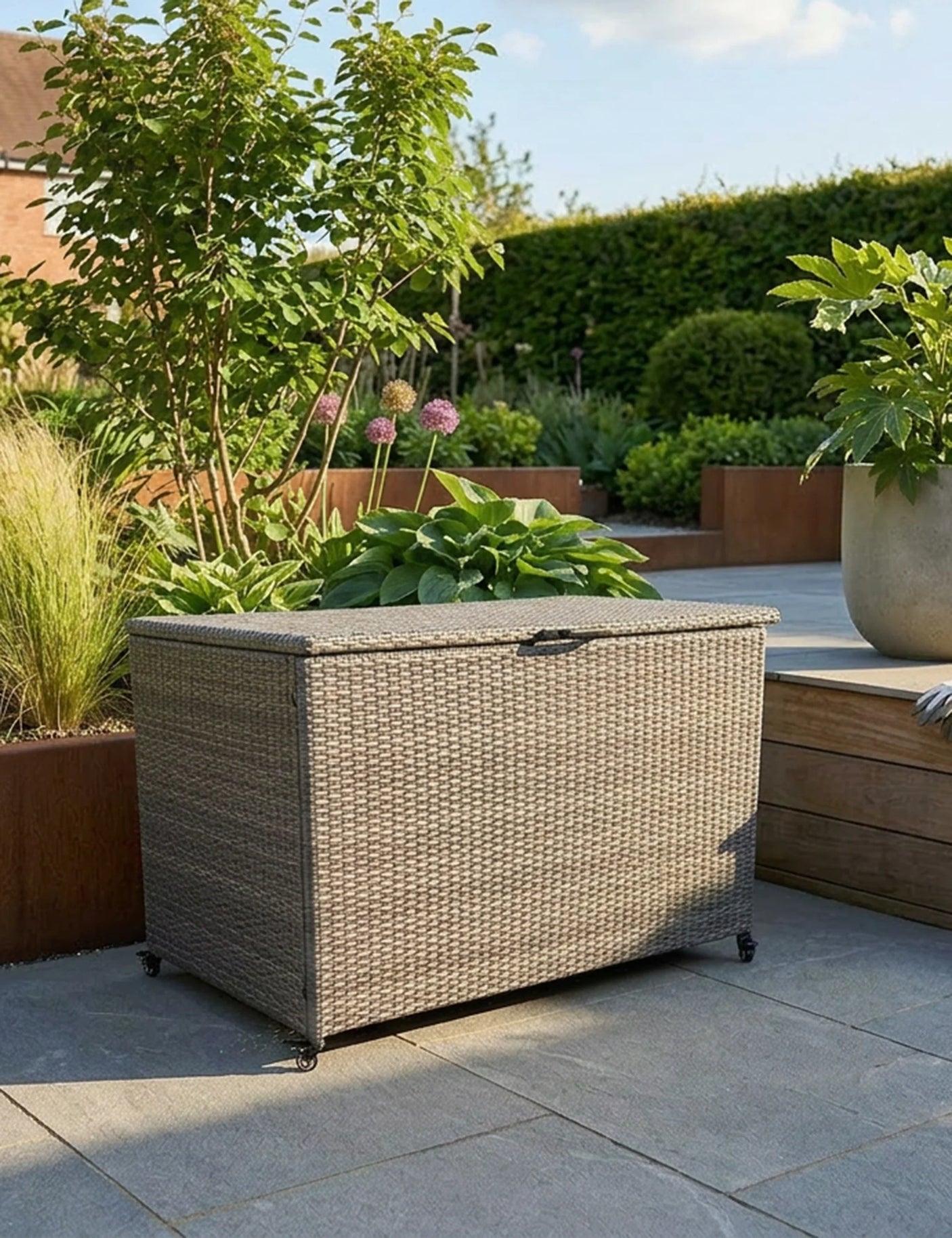 Rattan outdoor storage box with lid on patio surrounded by garden plants