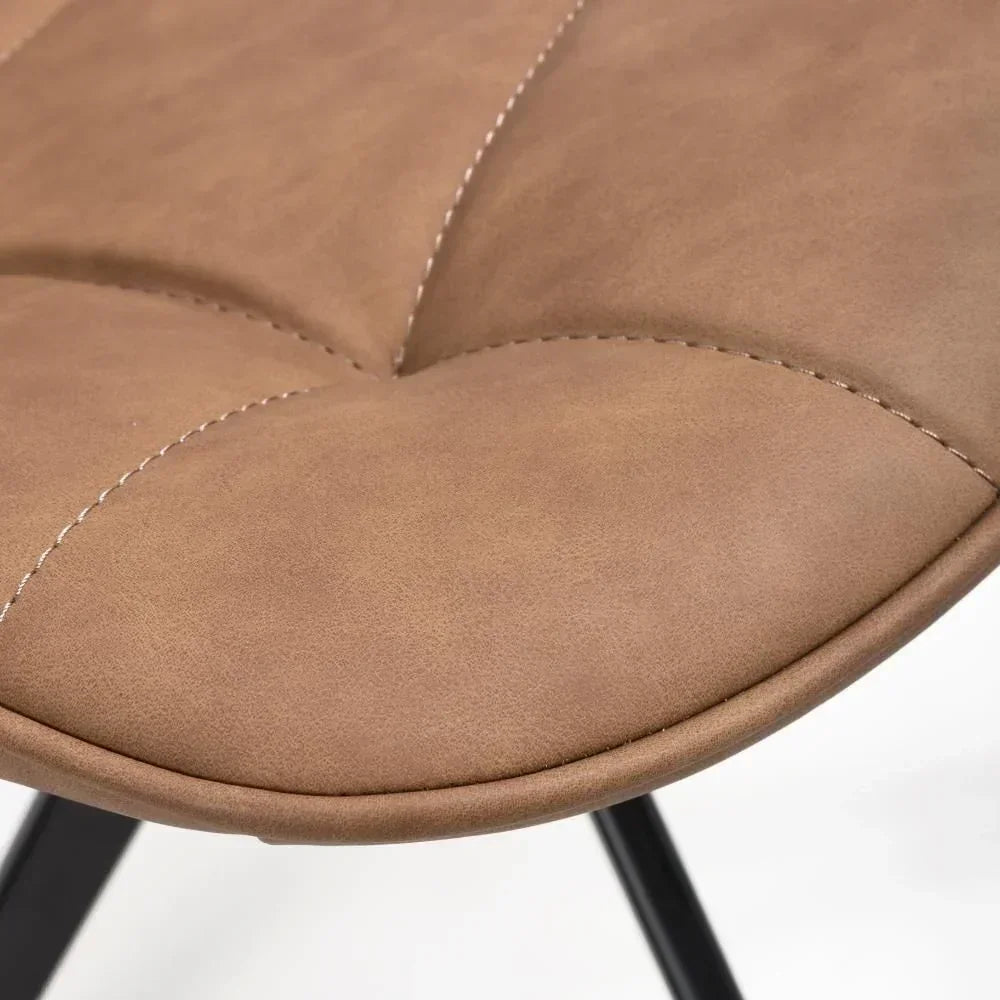 Close view of tan upholstered dining chair seat with visible stitching and black legs