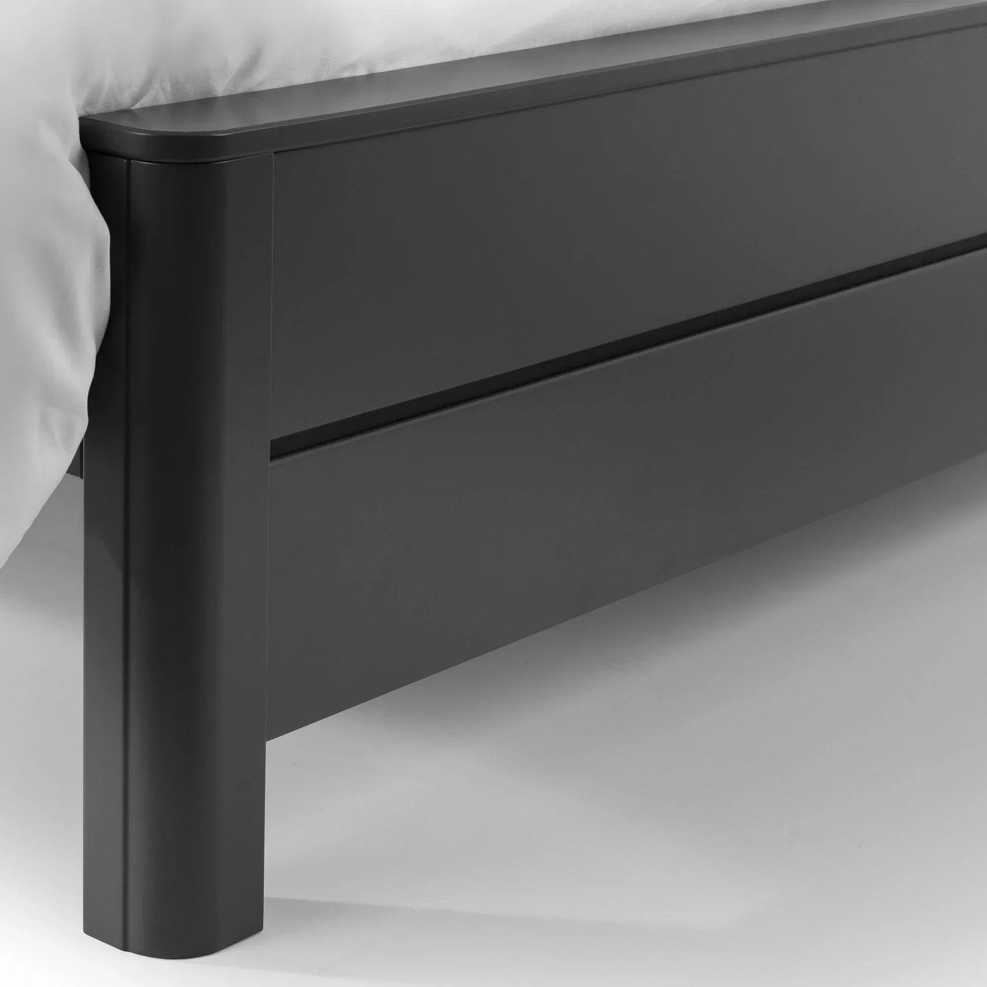 Closeup of black king bed frame footboard with clean lines and corner leg detail