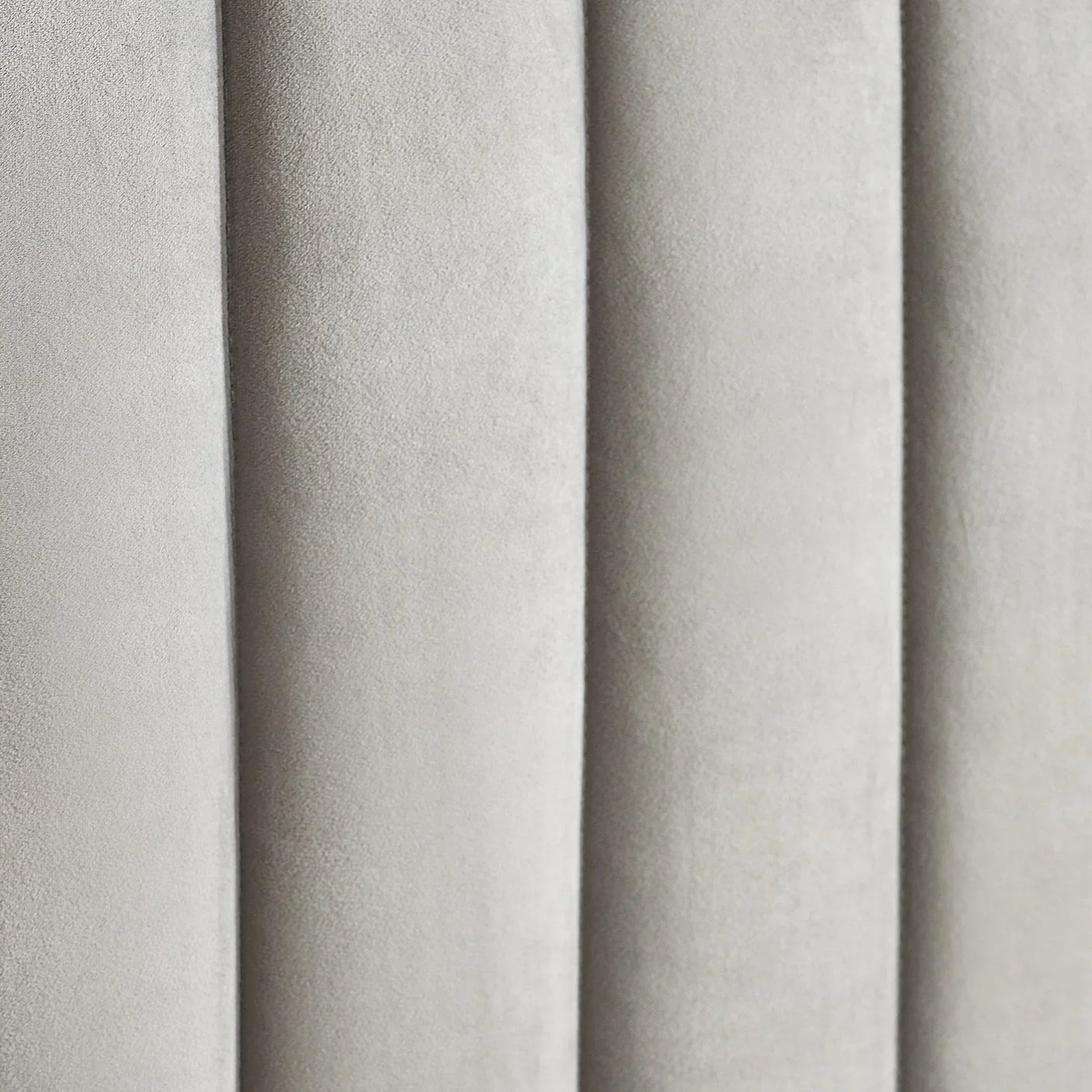 Close-up of grey upholstered bed headboard with vertical panel detailing