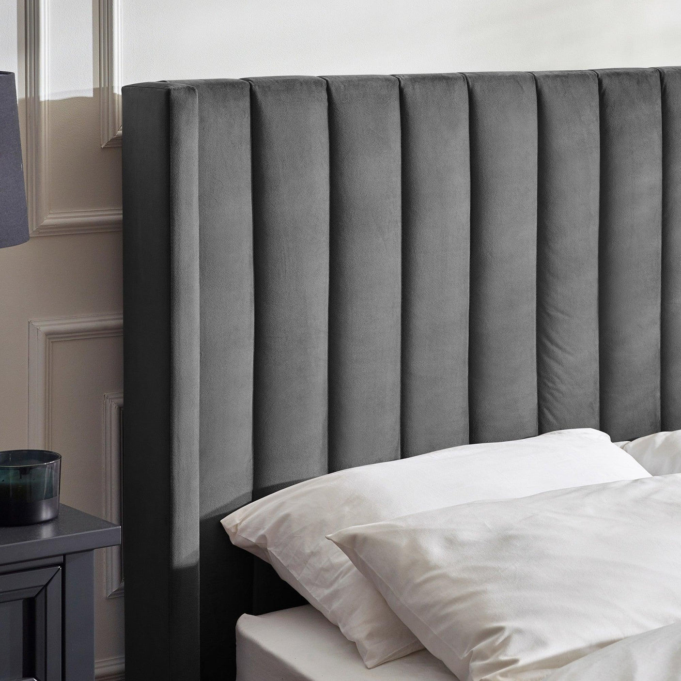 Grey upholstered bed with vertical panel headboard and white bedding