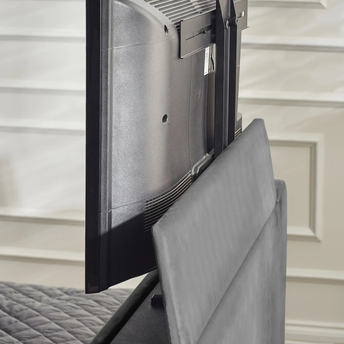Rear view of TV lift mechanism integrated in upholstered bed footboard