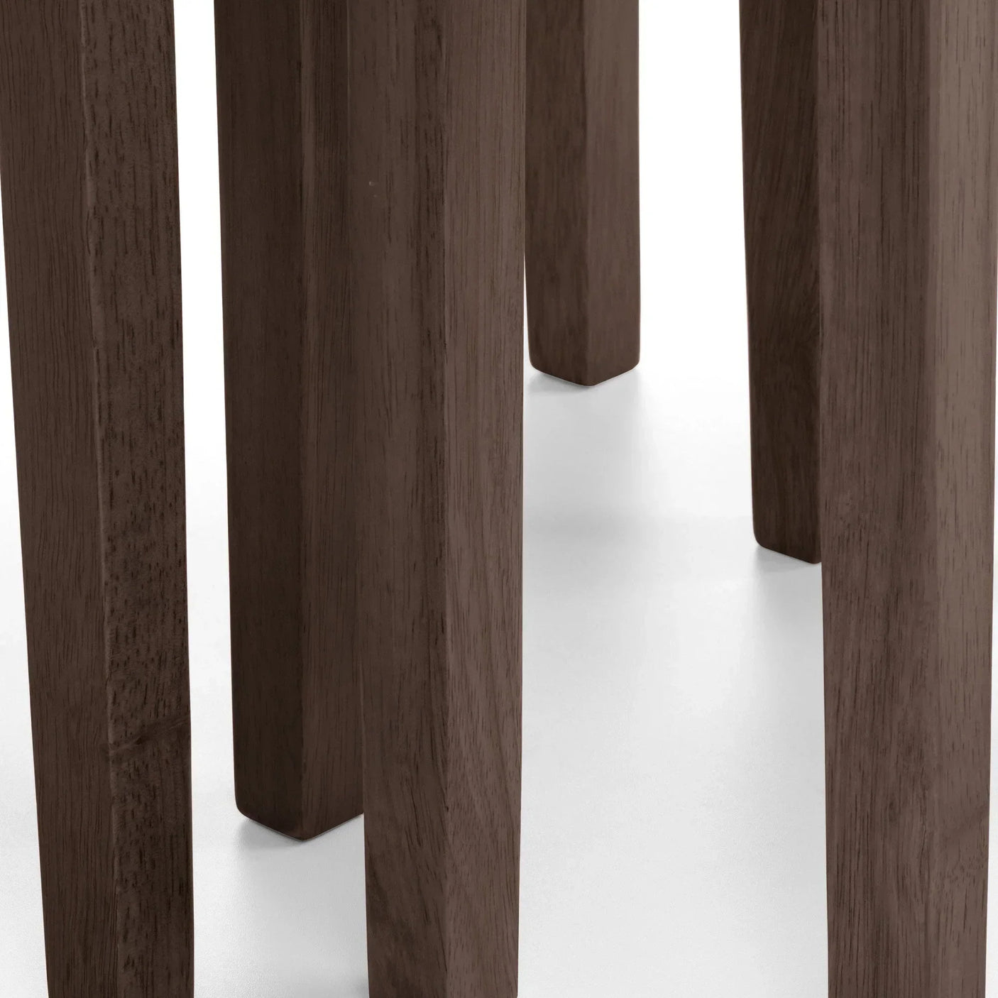 Close-up of dark wood dining table legs on light floor