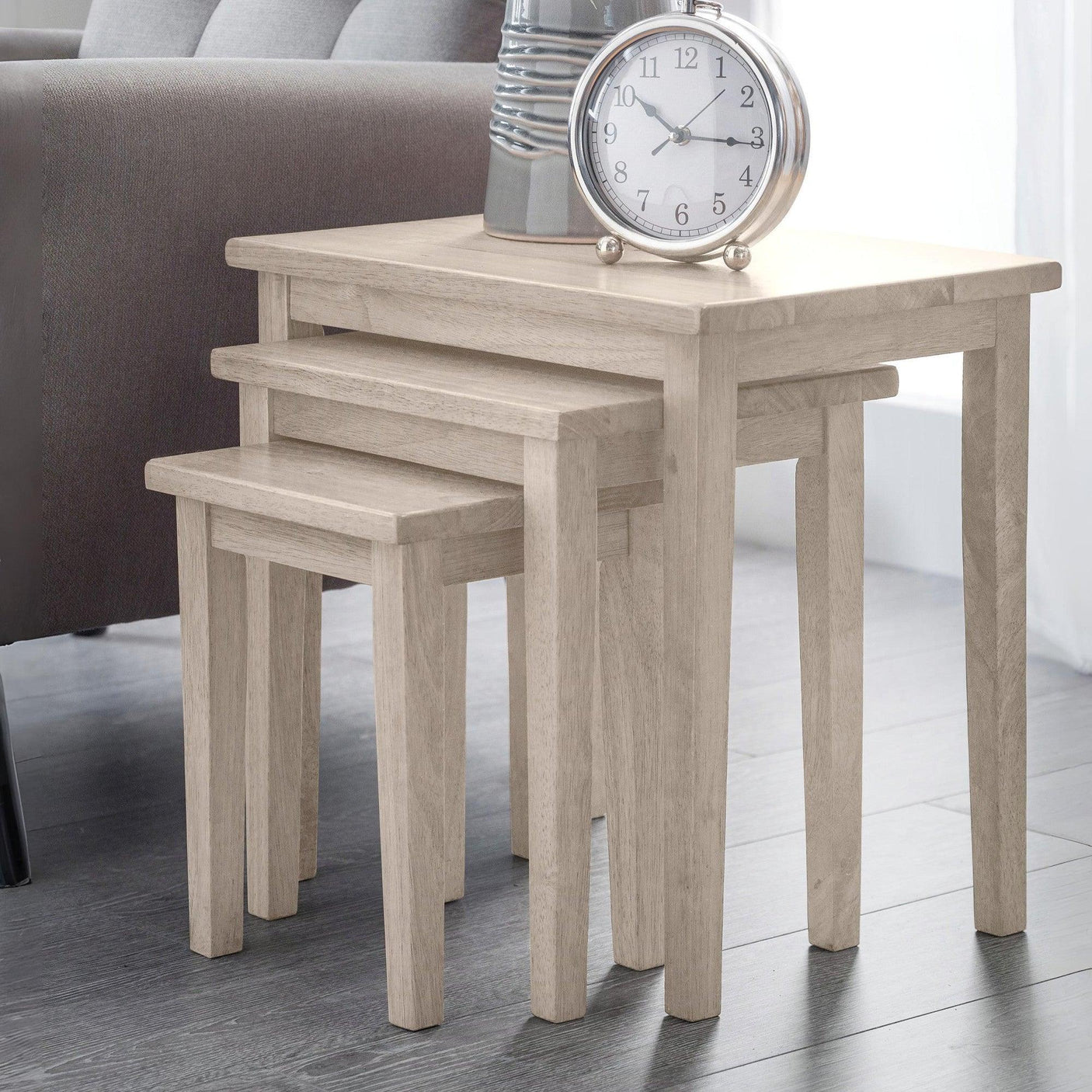Light oak nest of tables in living room, styled with tabletop clock and ceramic vase