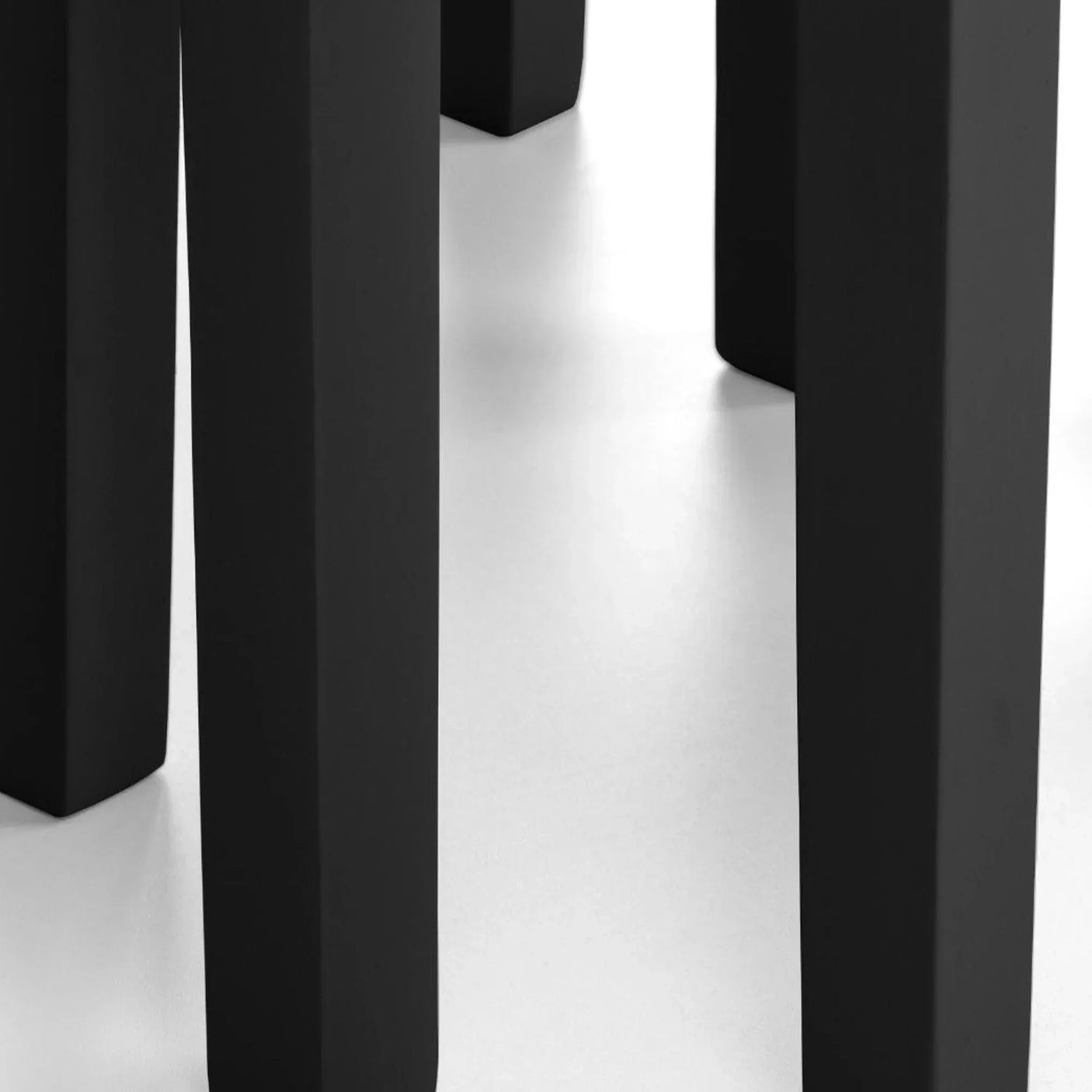 Close-up of black dining table legs on white floor, showing modern furniture detail