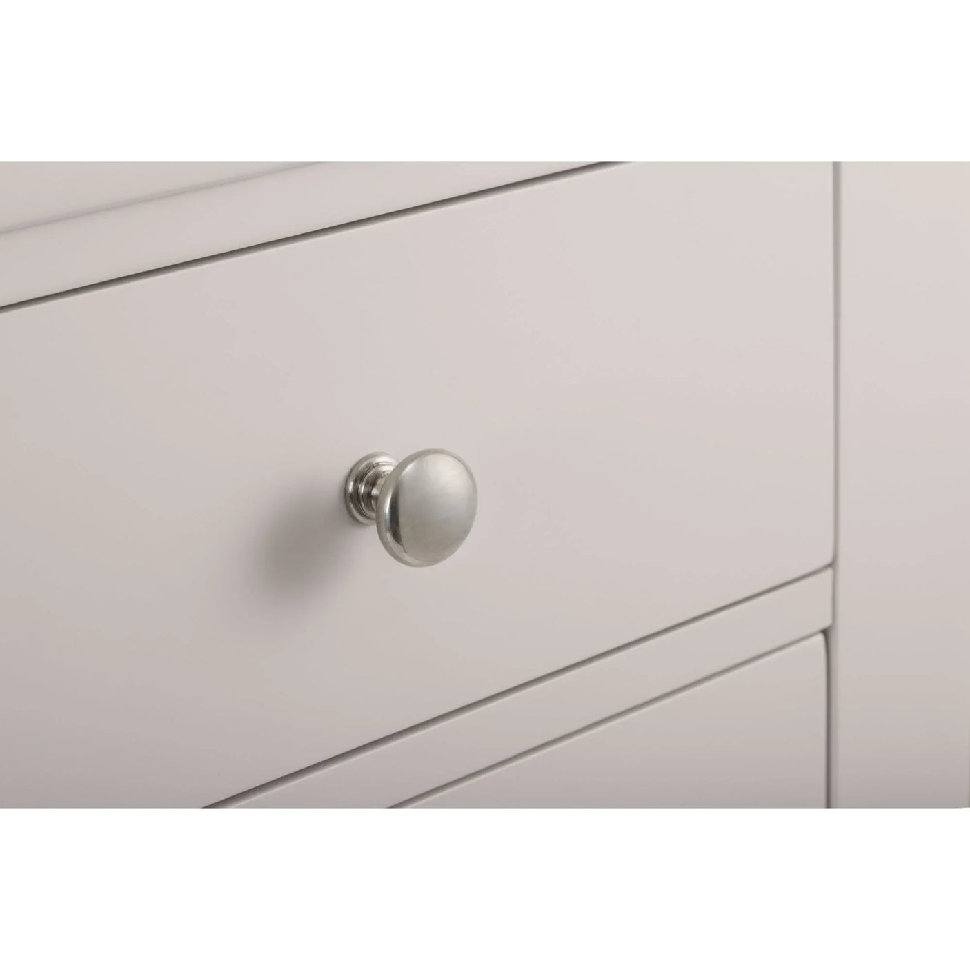 Light grey chest of drawers close-up showing round metal drawer handle and smooth finish