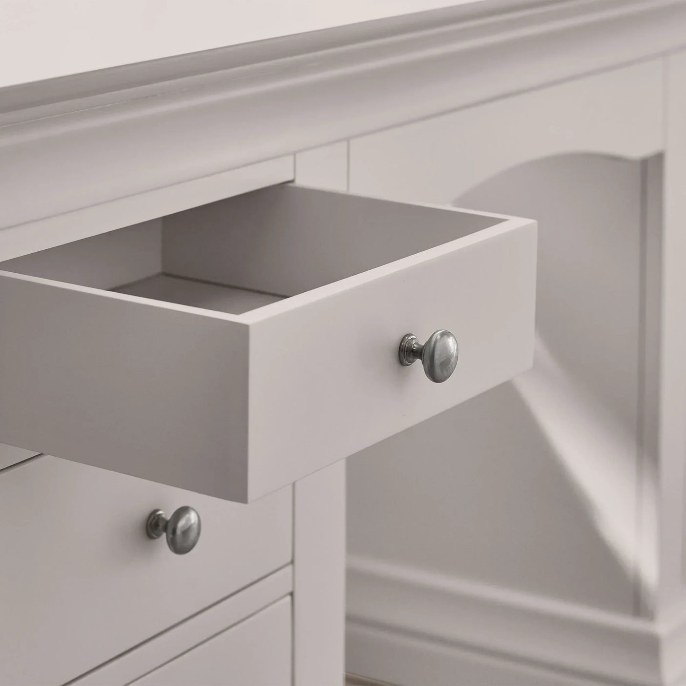Grey dressing table drawer open showing silver knob and painted wood detail