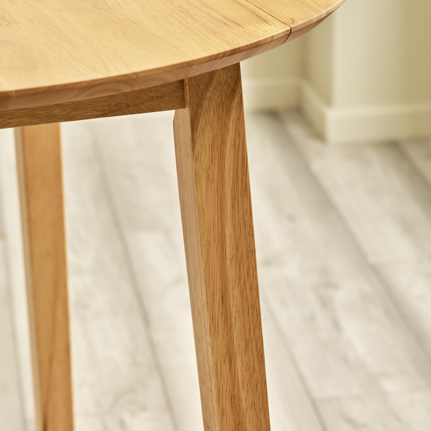 Close-up of smooth angled wood table leg on light-colored wooden floor