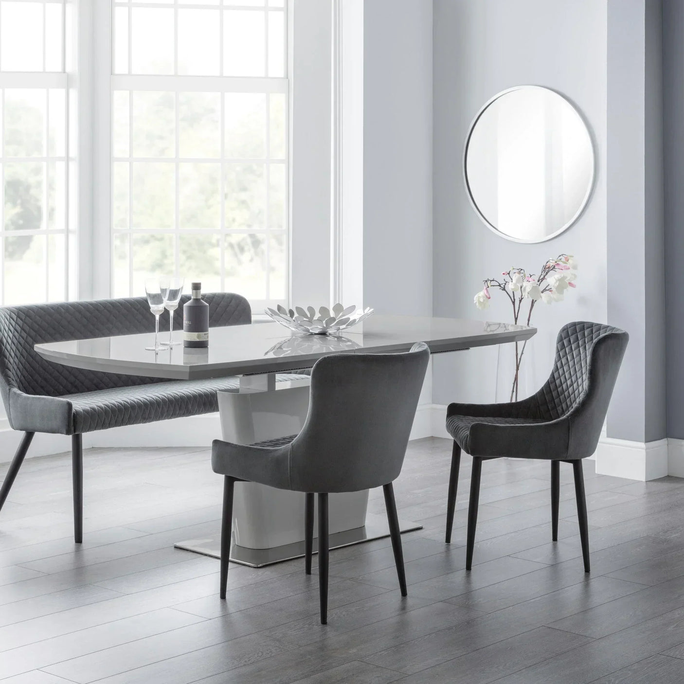 Grey velvet dining table set with quilted chairs and bench in modern bright dining room