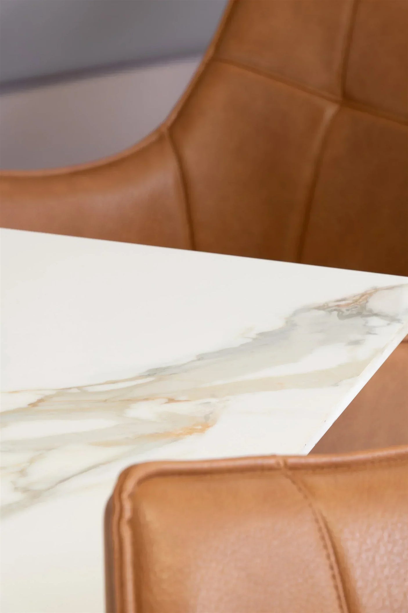 Close up of marble dining table corner and tan leather chair detailing