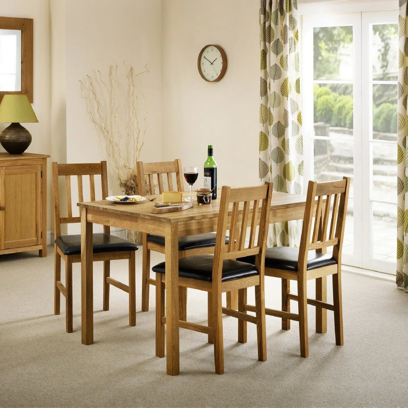 Oak dining table with four oak chairs and black seats in a bright carpeted dining room