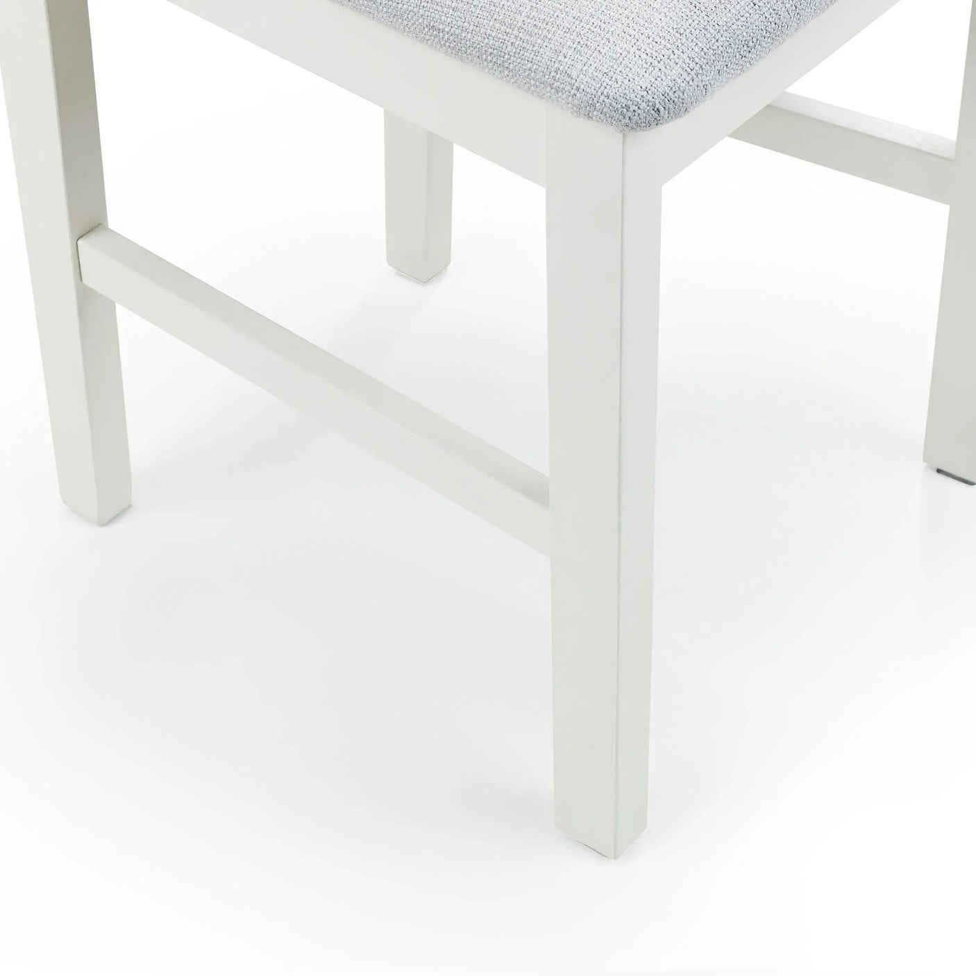 Ivory dining chair leg and light fabric seat corner close-up on white background