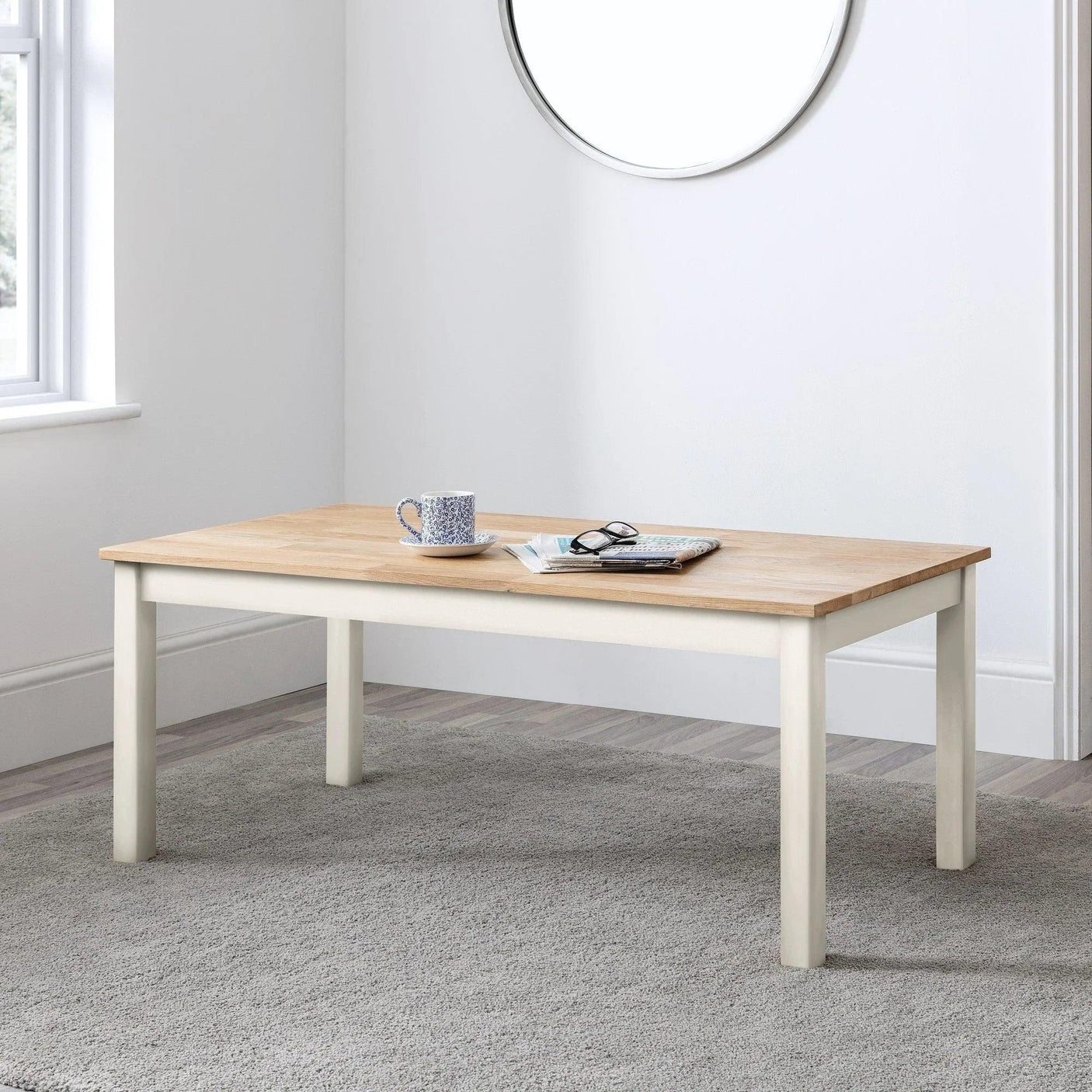 White and oak coffee table with cup, book, and glasses in modern living room setting