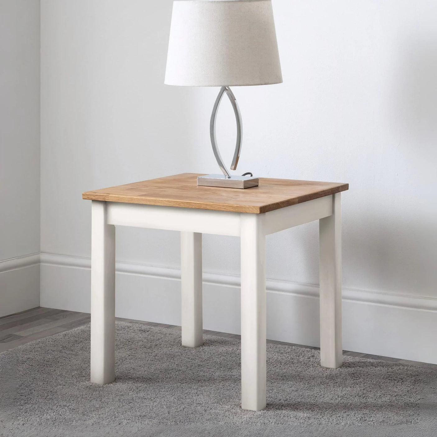 Oak and painted wood side table with lamp on grey carpeted floor