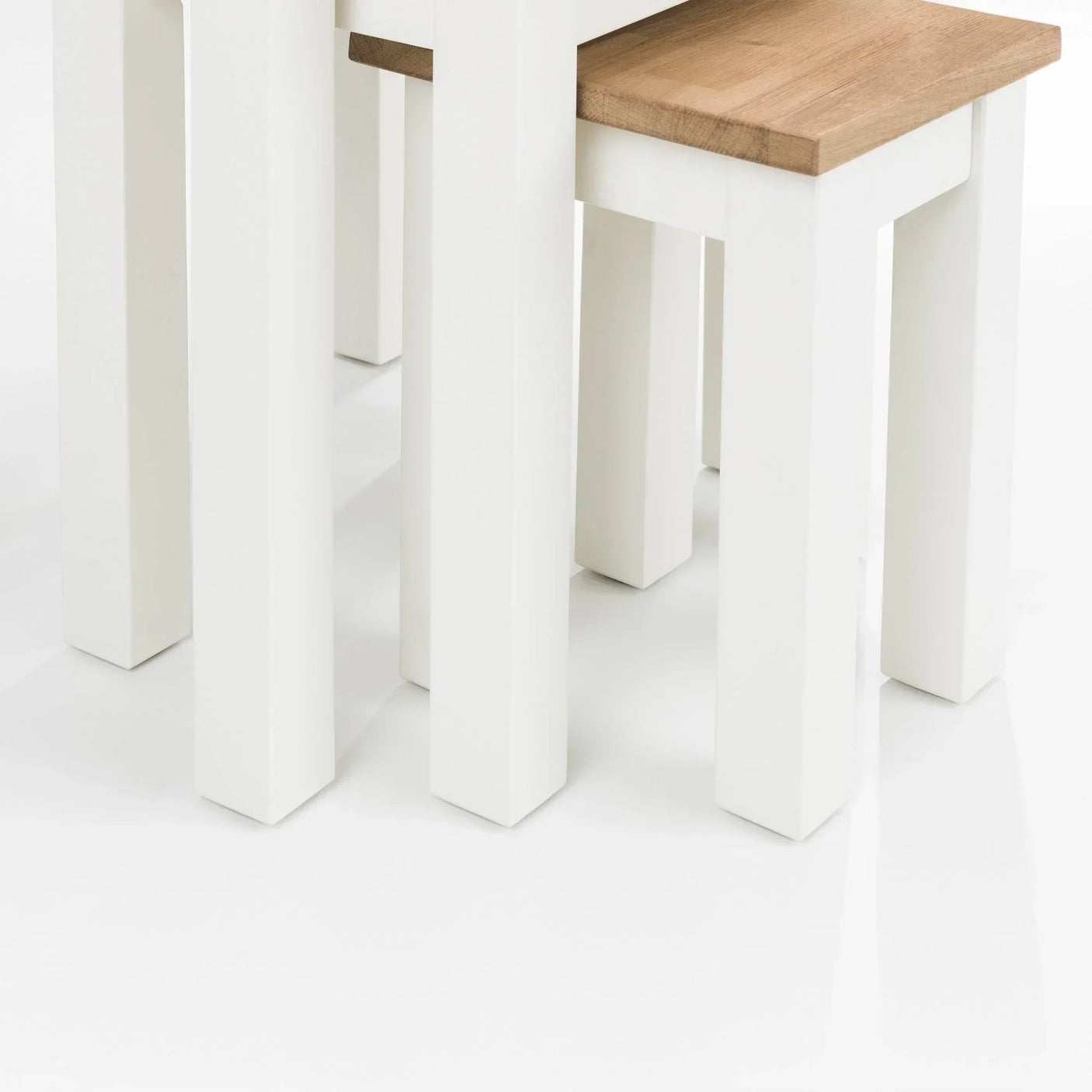 White oak nest of tables with wooden tops and painted white legs, close-up corner view