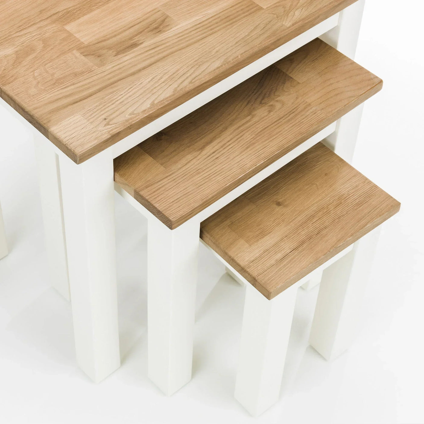 White oak nesting tables set with natural wood tops and white legs in stacked arrangement
