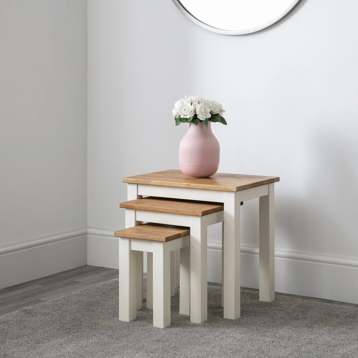 White and oak nest of tables set with pink vase of white flowers on top in modern room