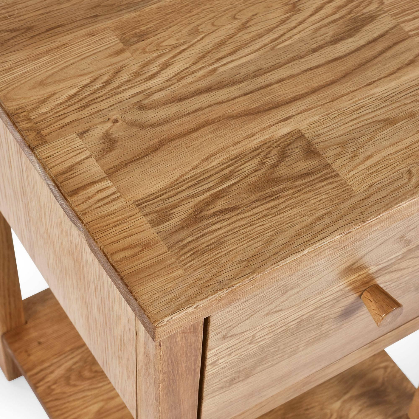 Solid oak bedside table with drawer and shelf, natural wood grain finish, top corner view