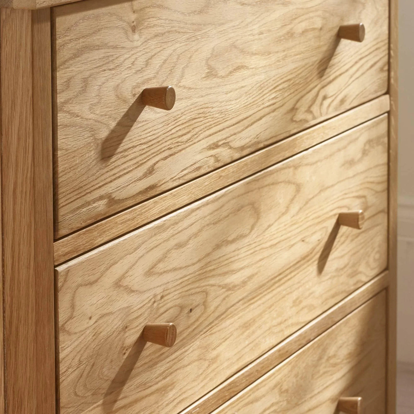 Close view of oak chest of drawers with wooden handles and natural wood grain finish