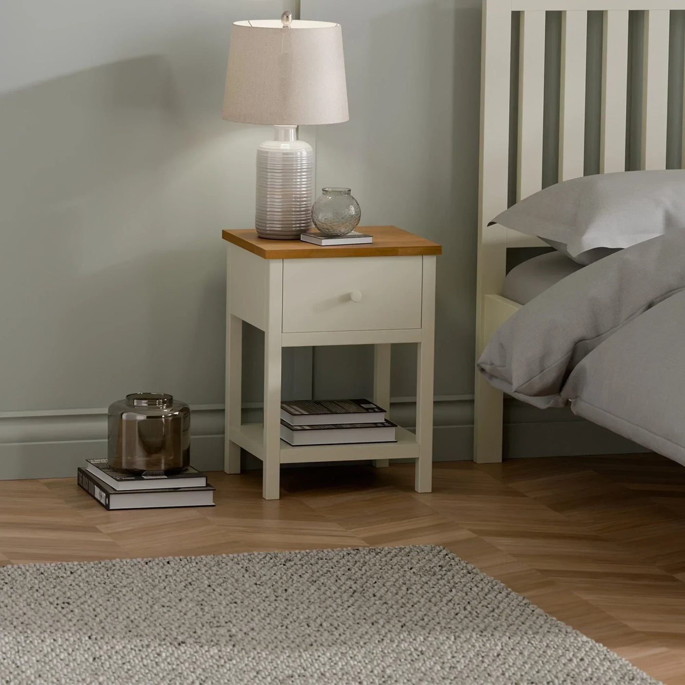 Ivory oak bedside table with single drawer, lamp, and books in modern bedroom setting