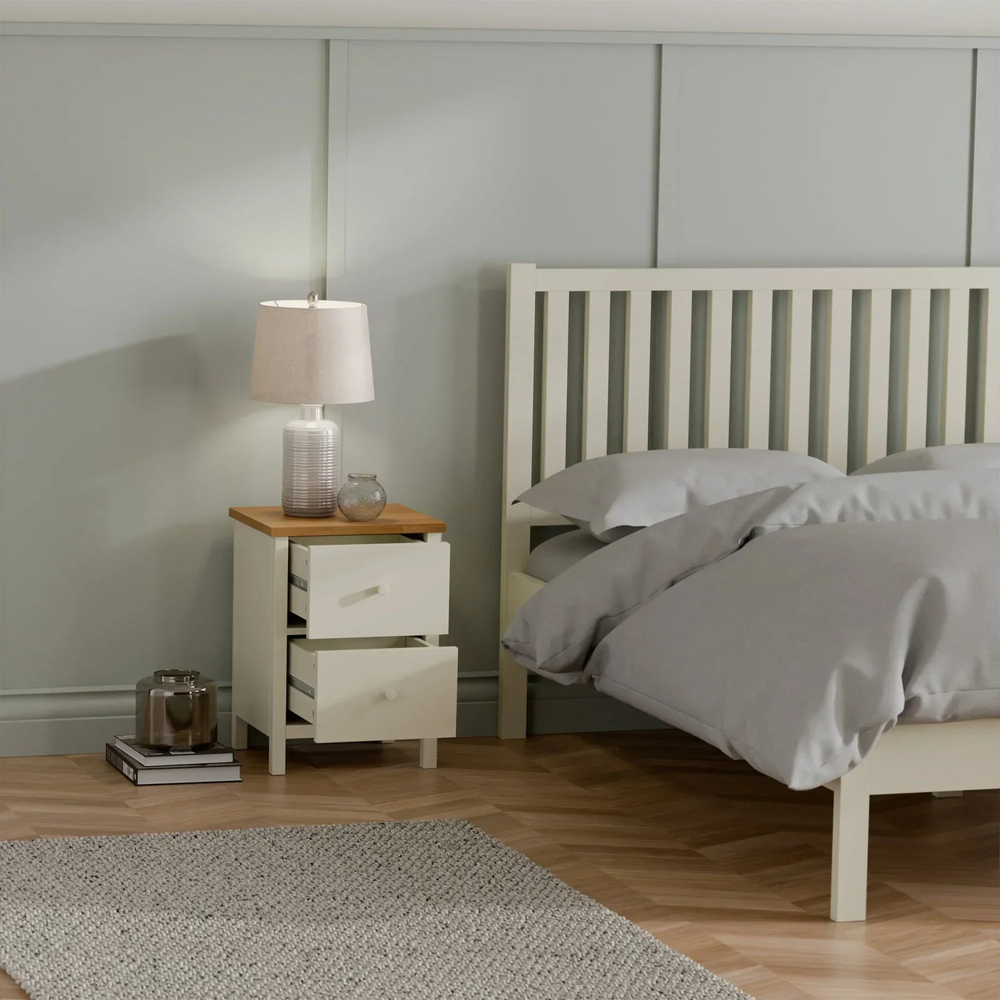 Ivory two drawer bedside table with oak top beside bed, lamp and decor in modern bedroom
