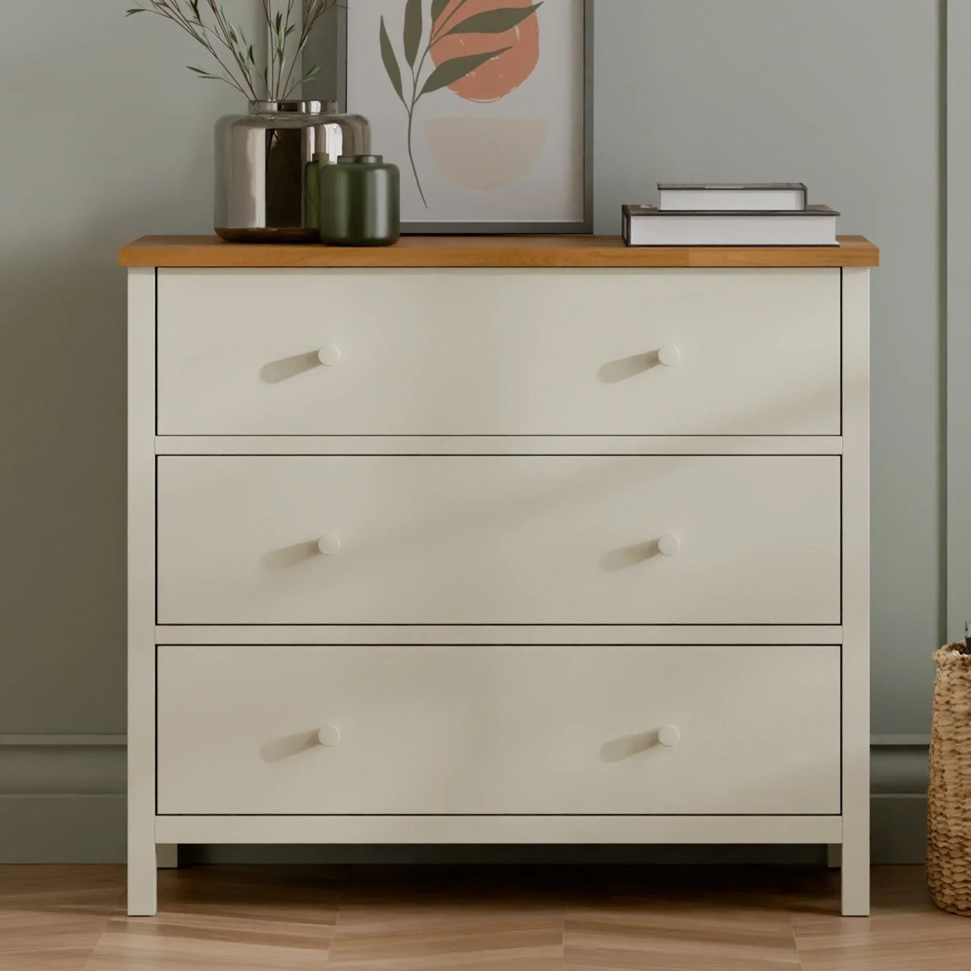 Cream three drawer chest of drawers with wooden top in modern bedroom setting