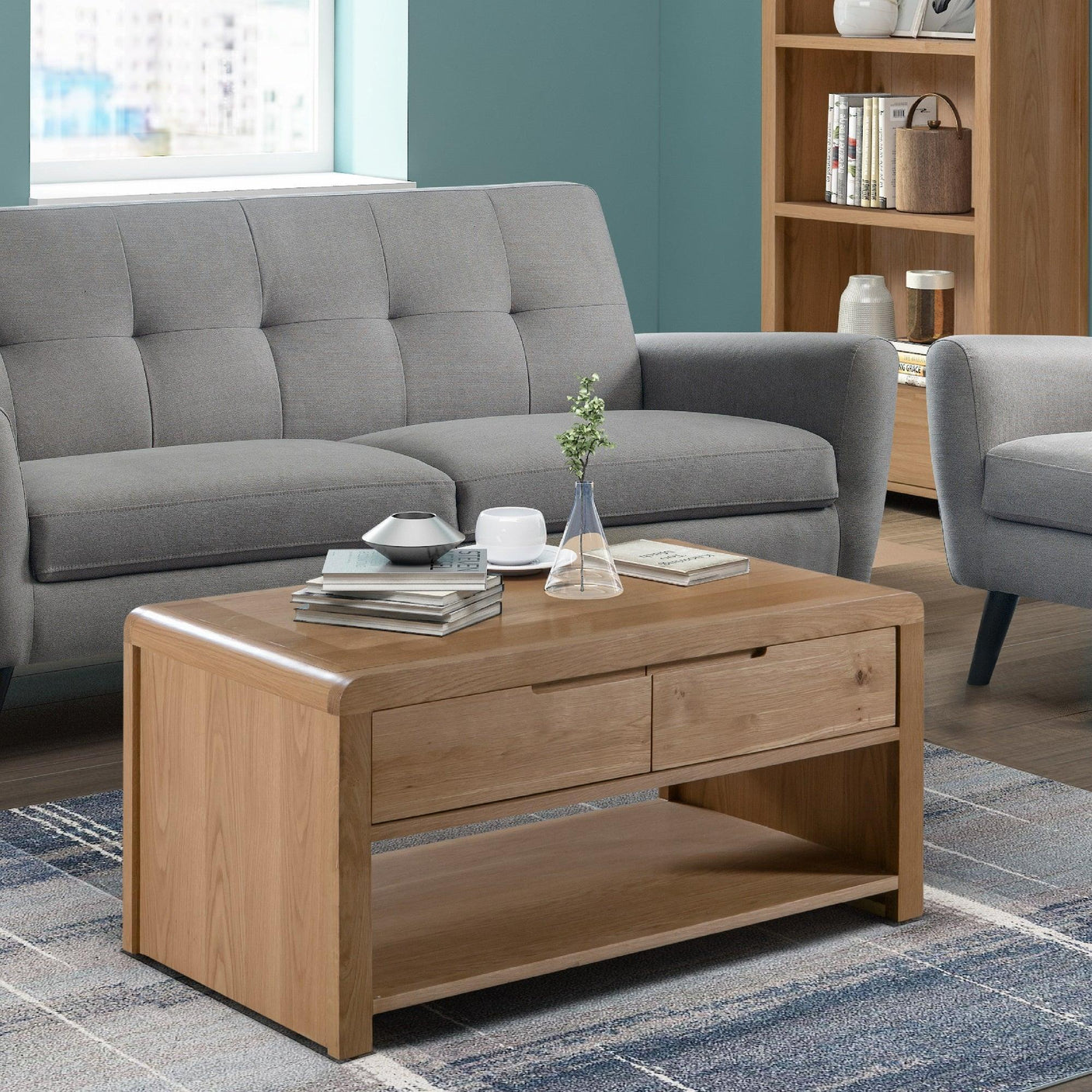 Oak coffee table with drawers and shelf in living room, paired with grey sofa and armchair
