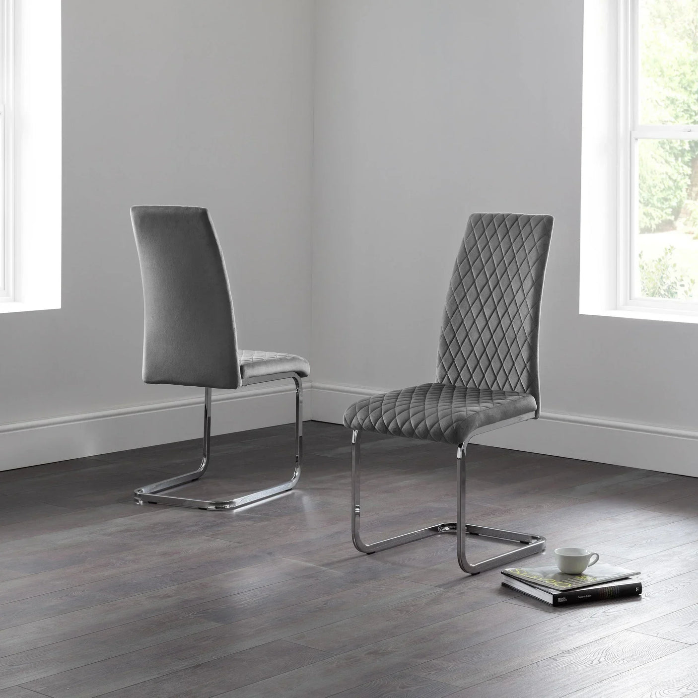 Grey velvet cantilever dining chairs with quilted seat designs on dark wood floor