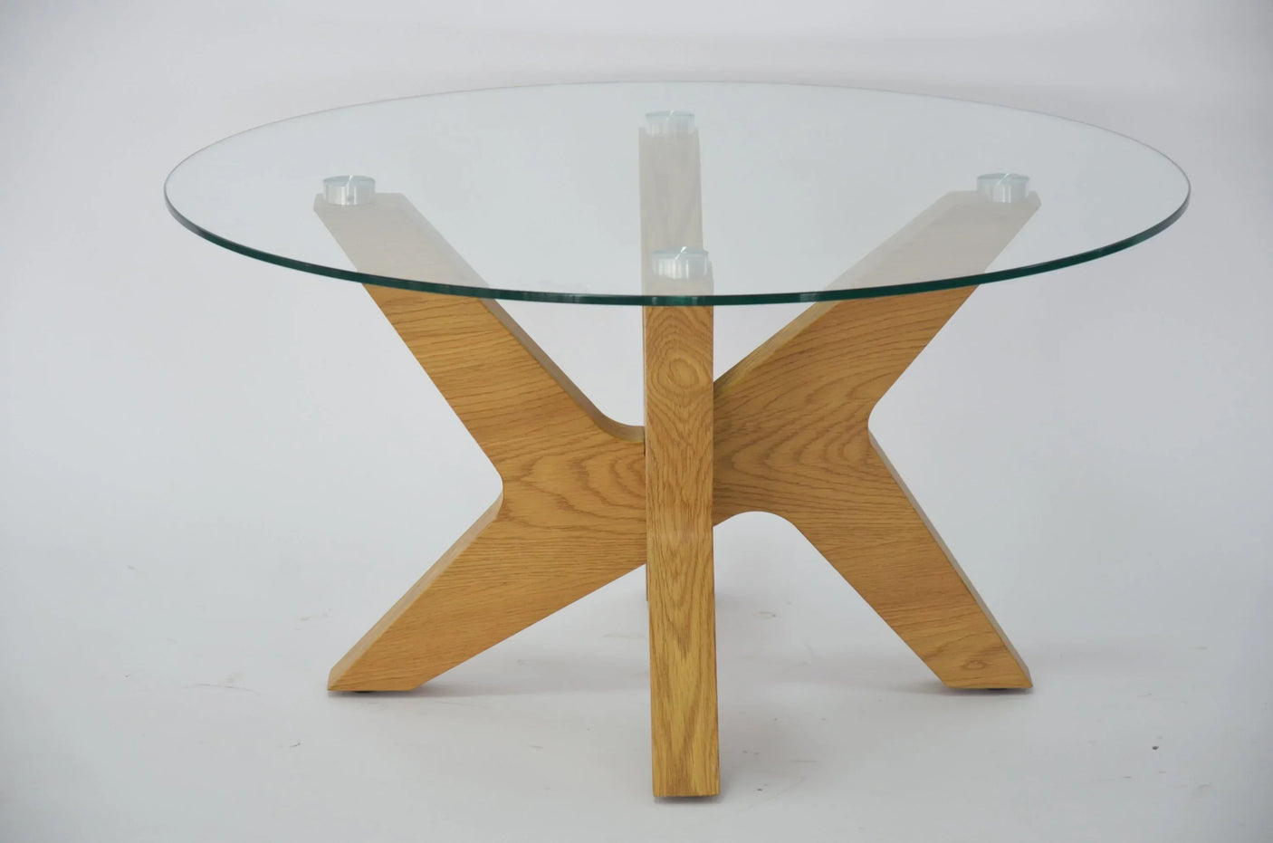 Round glass top coffee table with oak wood base on white background